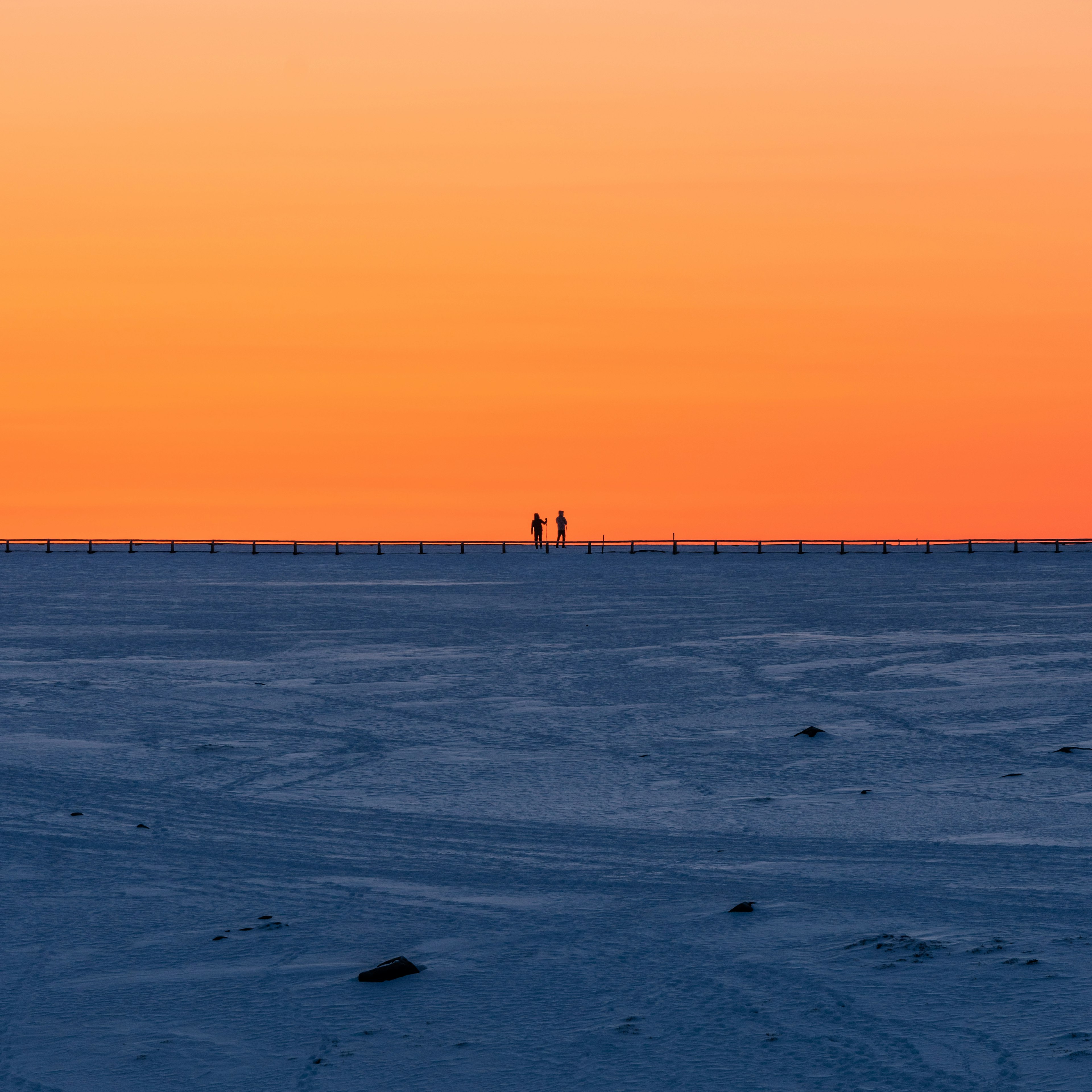 Silhouettes de deux personnes sous un coucher de soleil orange