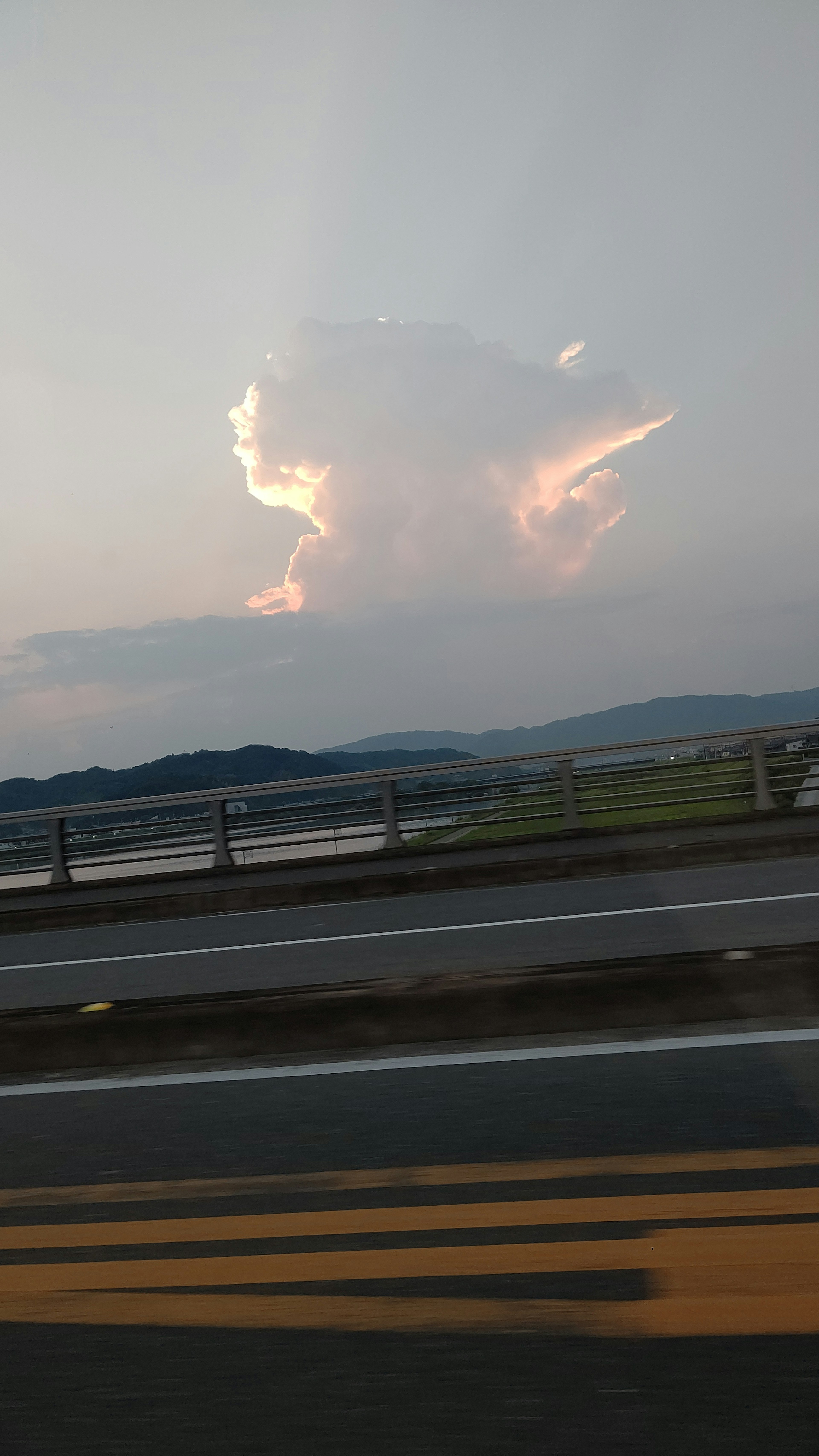 雲と夕焼けの景色が広がる道路の風景