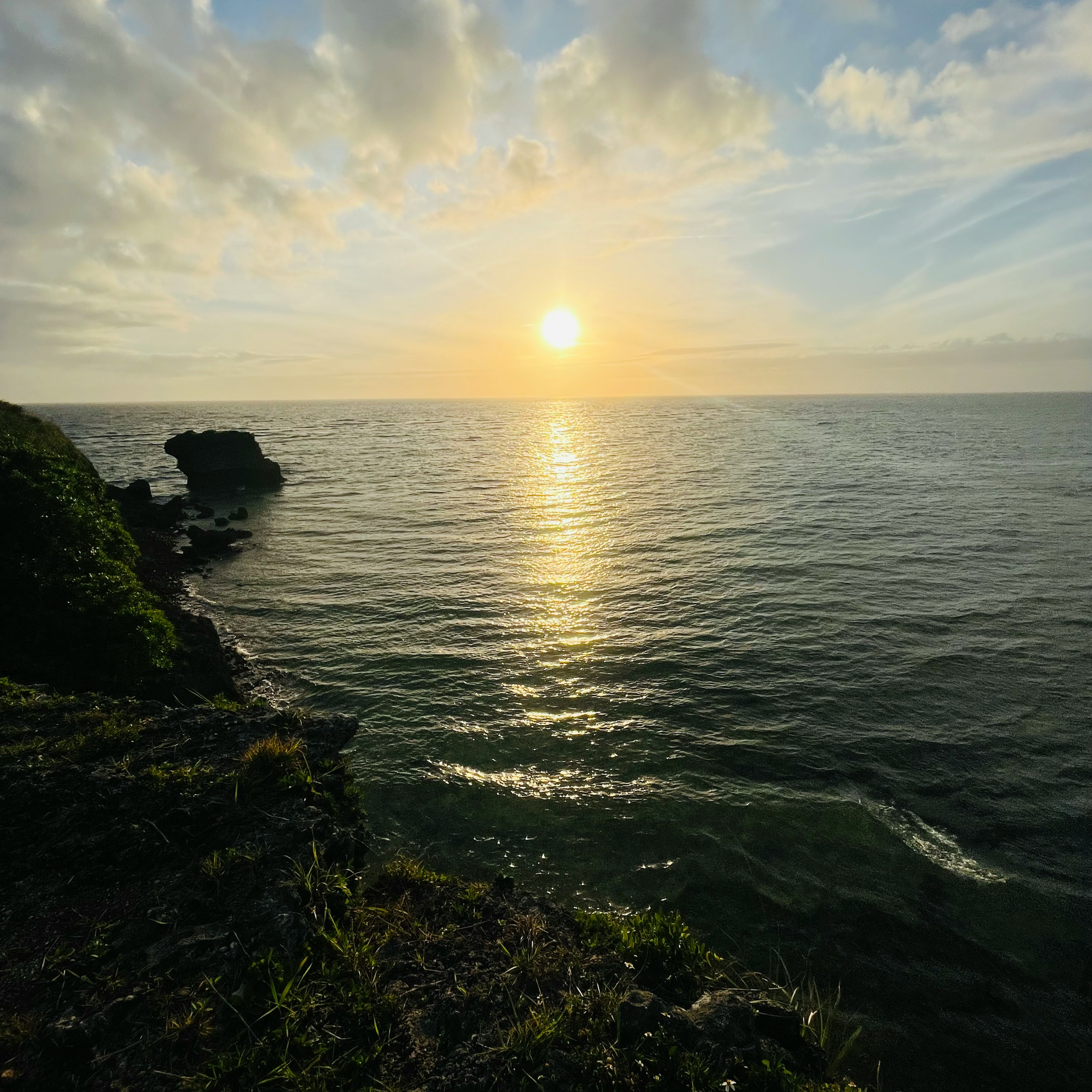 夕日が海に映る美しい風景 磯と草がある崖からの眺め