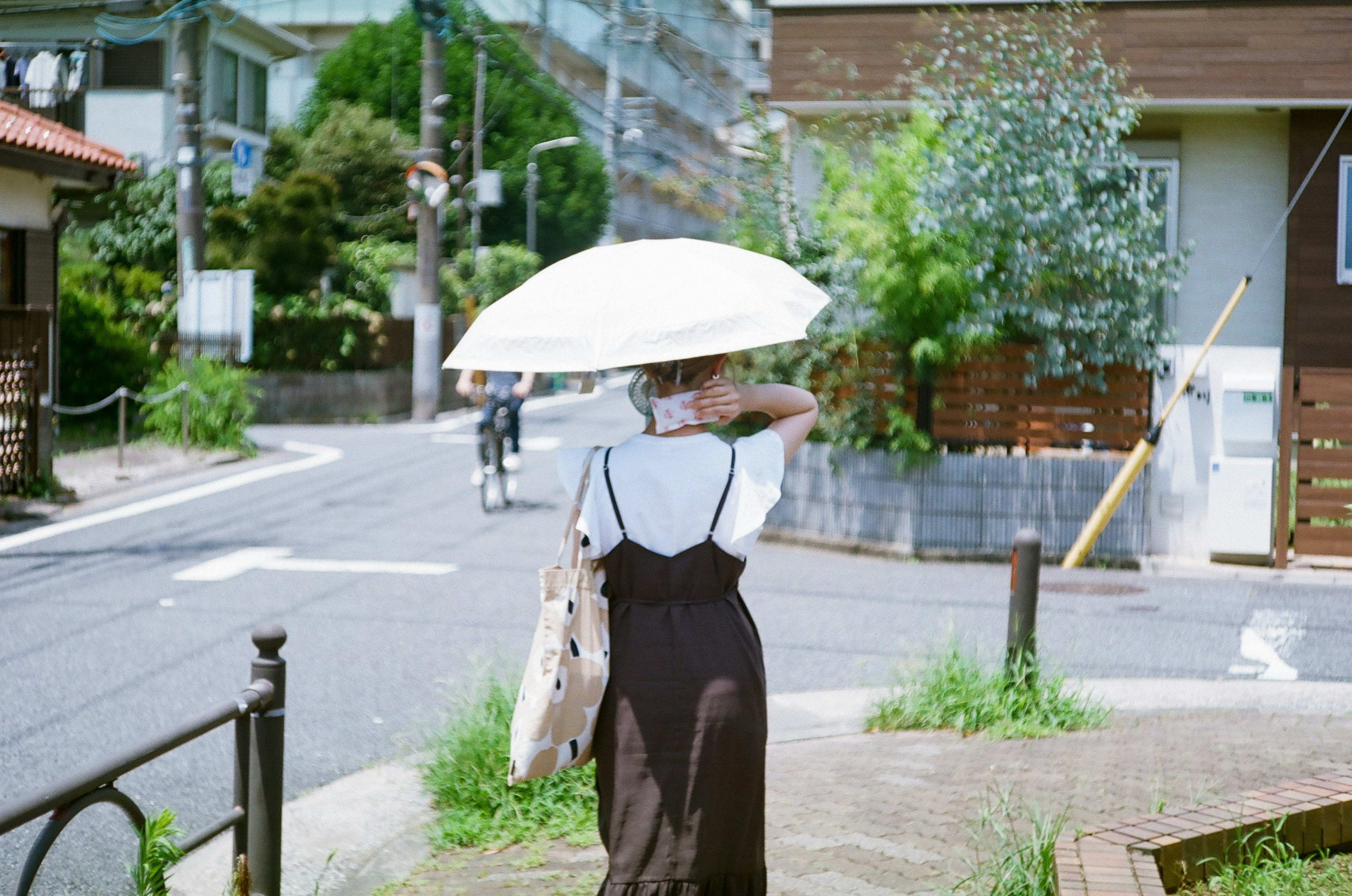 傘を持った女性が街角を歩いている様子