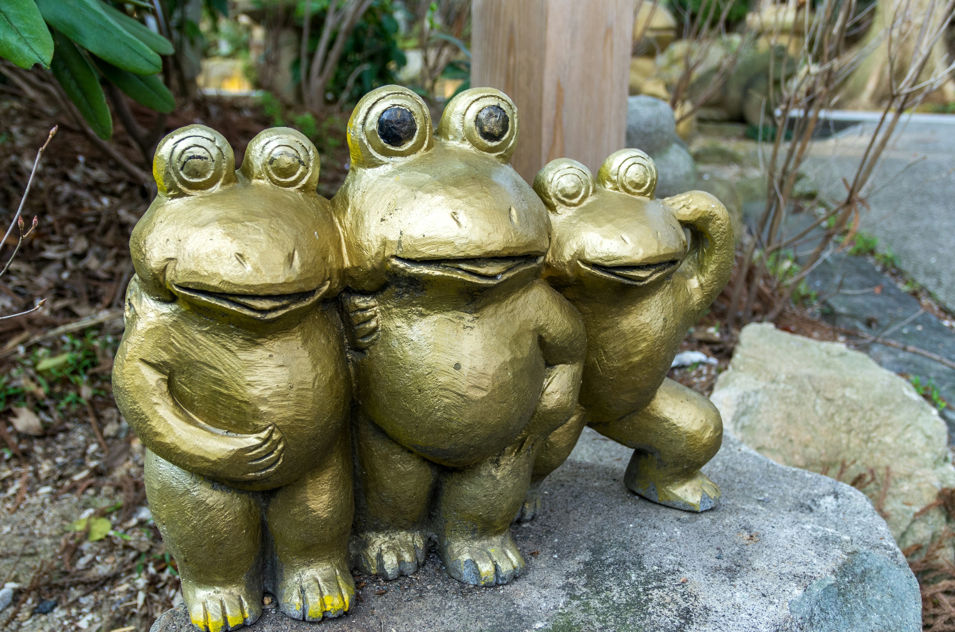 Trois statues de grenouilles dorées debout ensemble