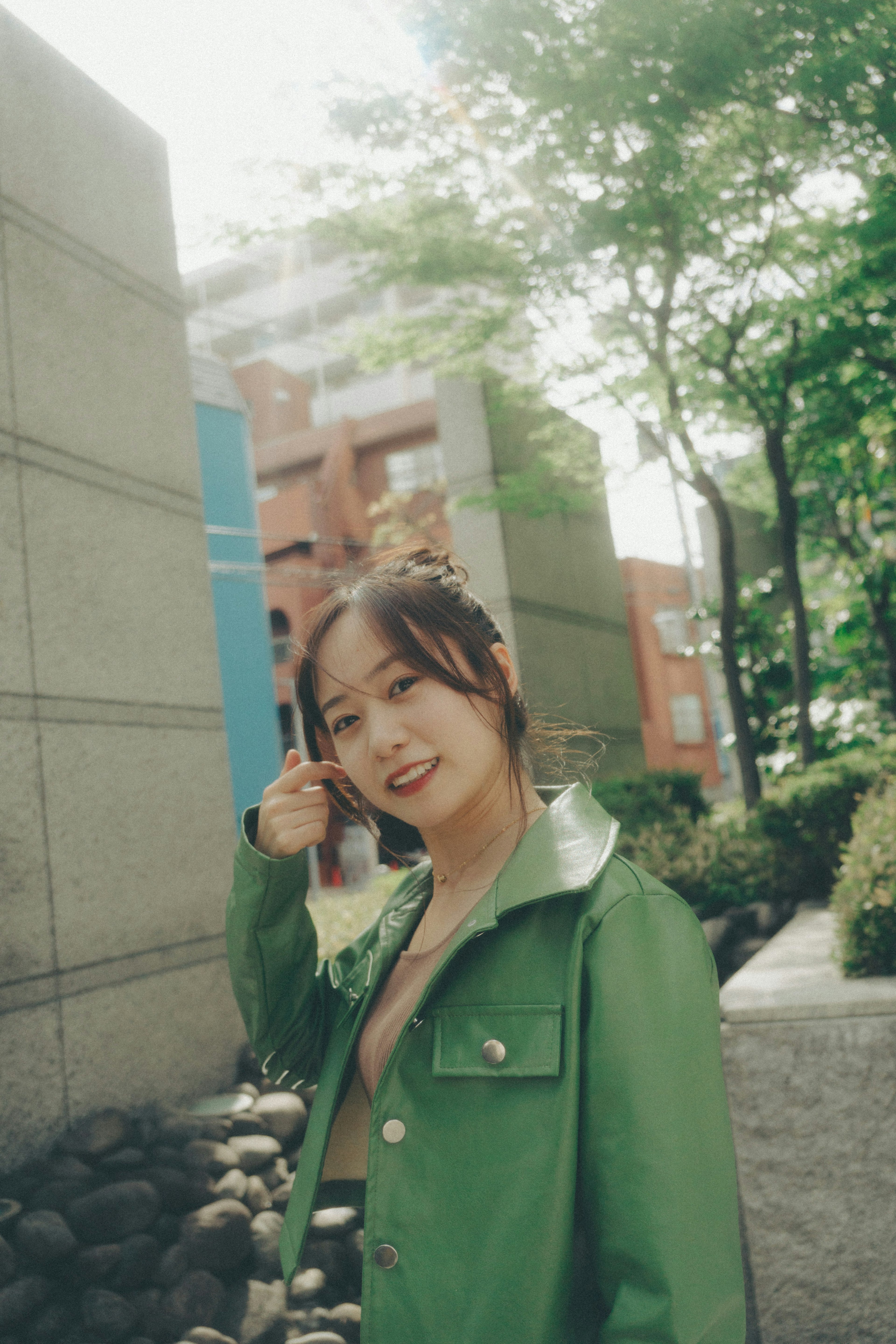 A woman in a green jacket smiling in a park