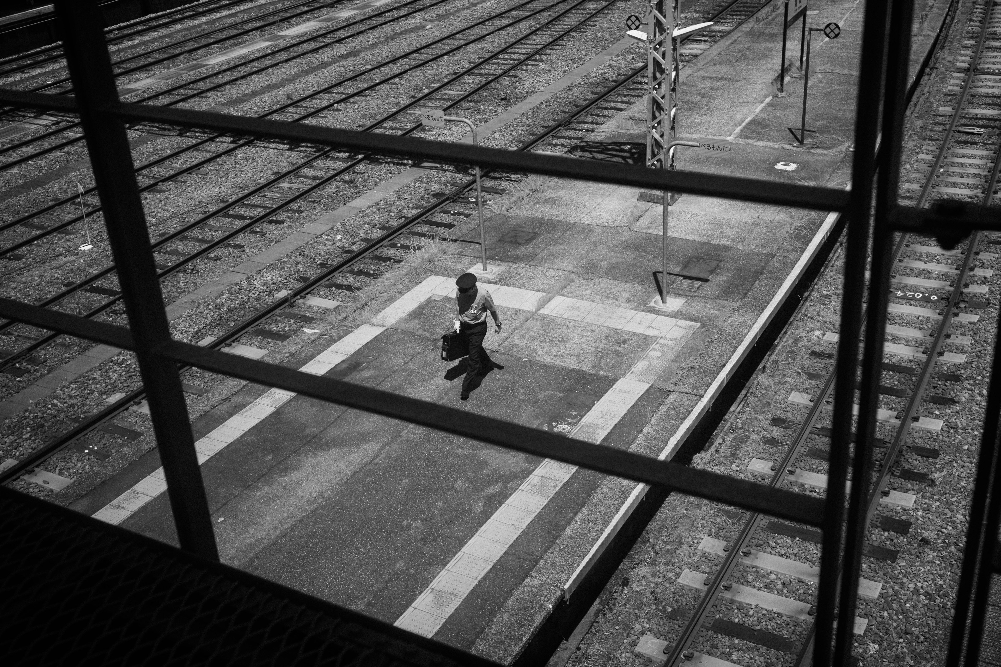 Une personne marchant sur un quai dans une gare en noir et blanc