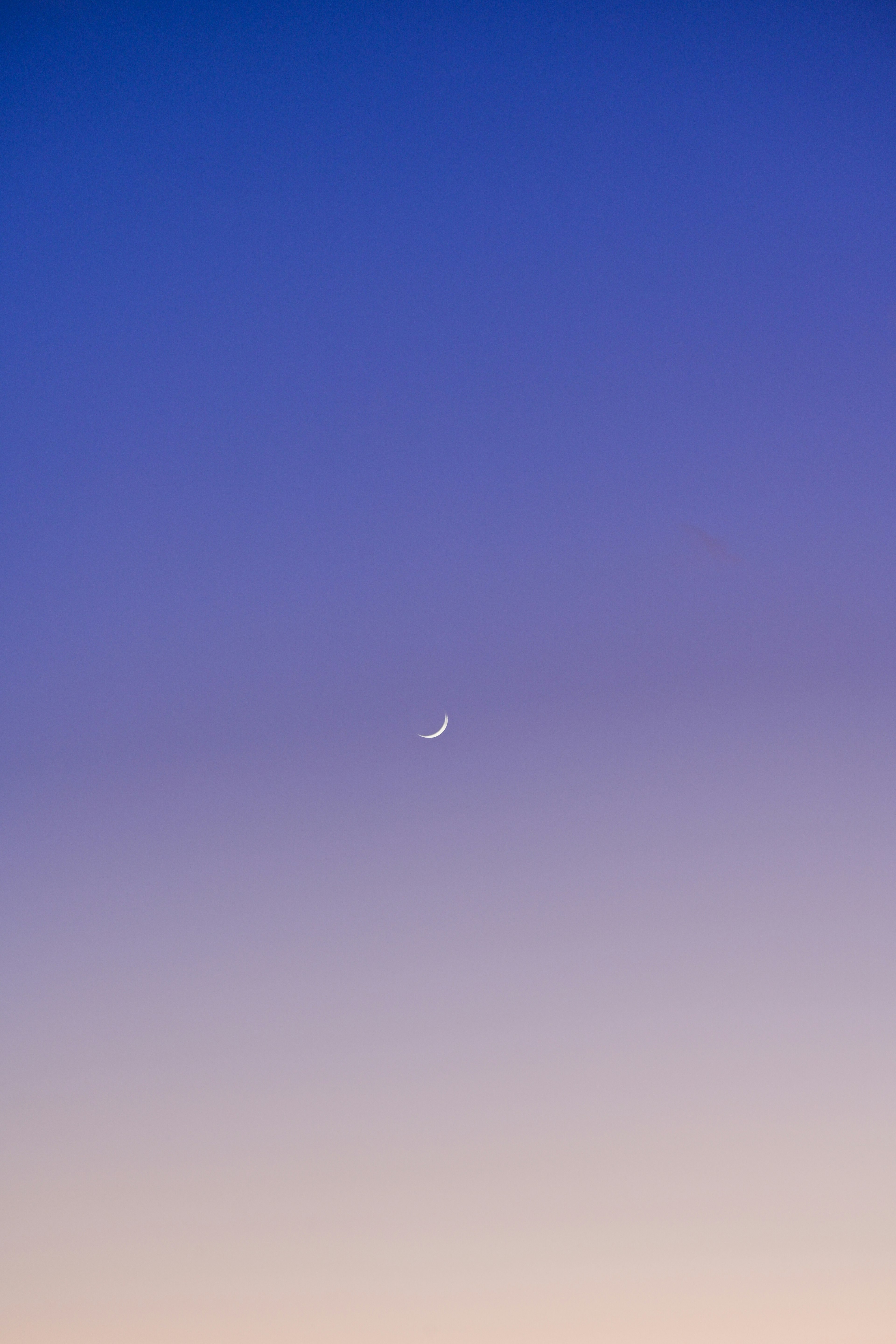 A small crescent moon in a twilight sky