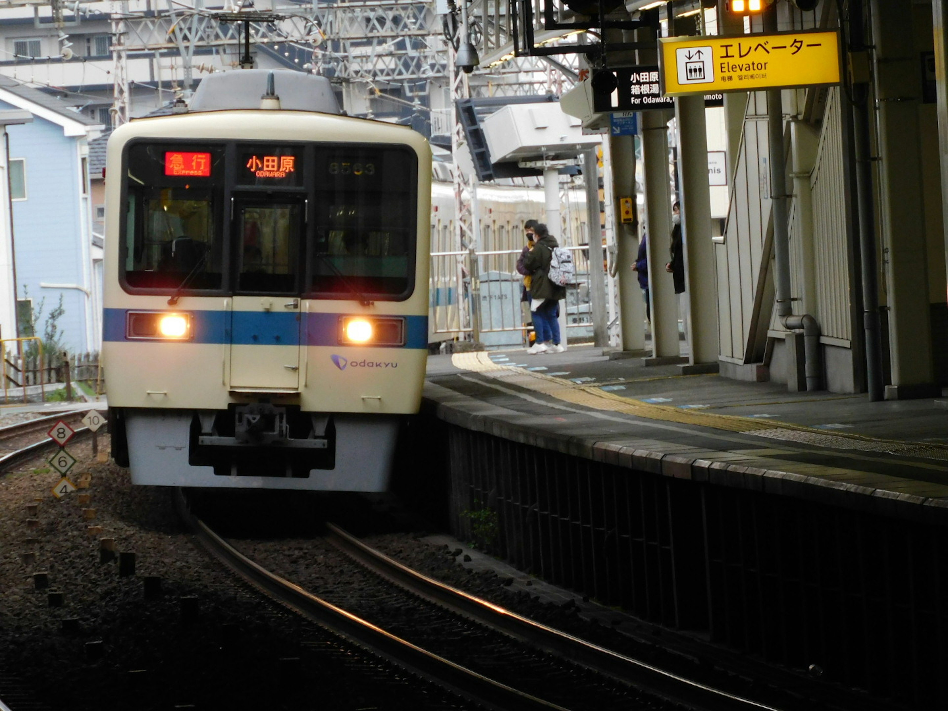 Zug, der an einem Bahnhof mit Fahrgästen auf dem Bahnsteig ankommt