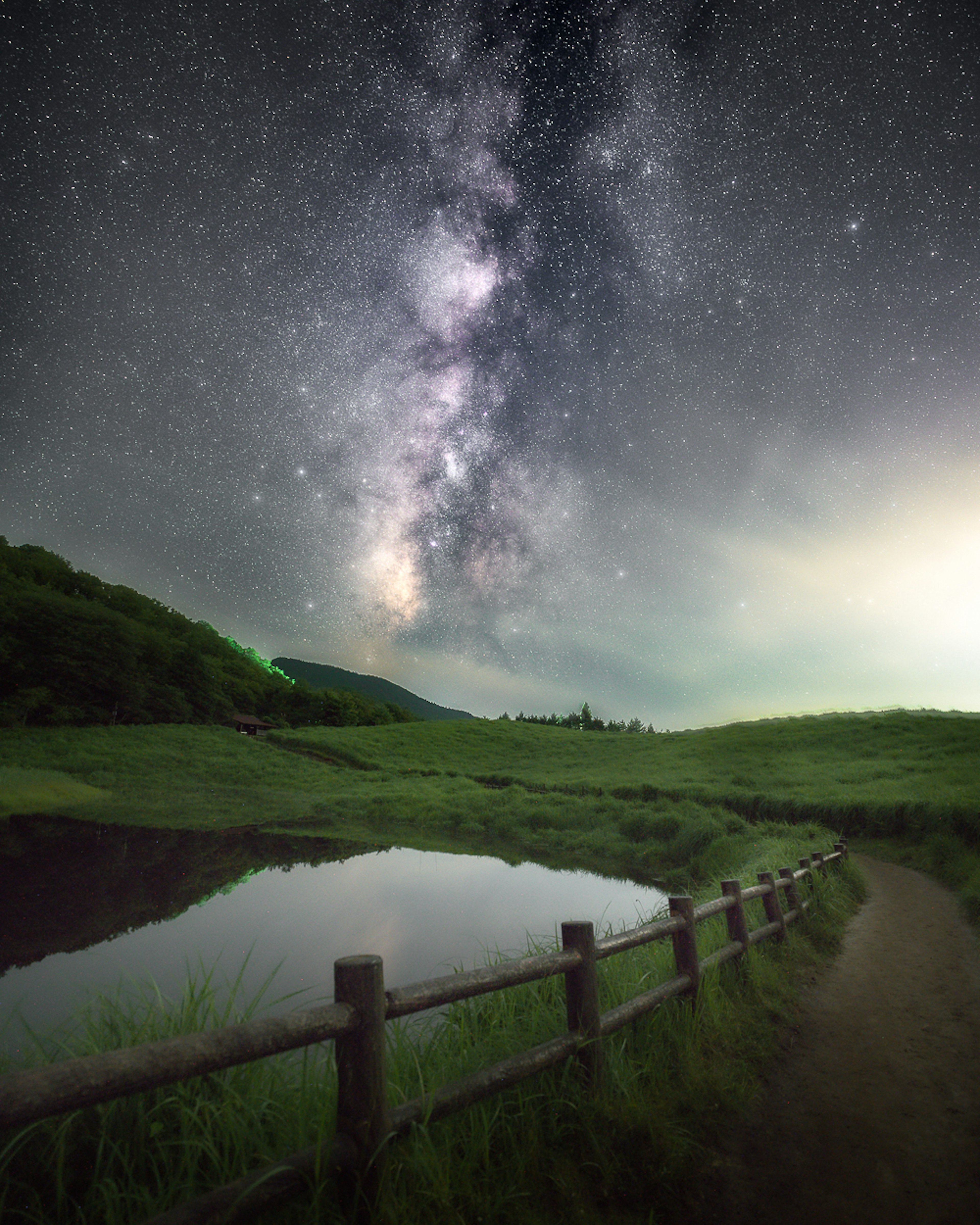 Paesaggio sereno con un lago che riflette il cielo stellato e la Via Lattea