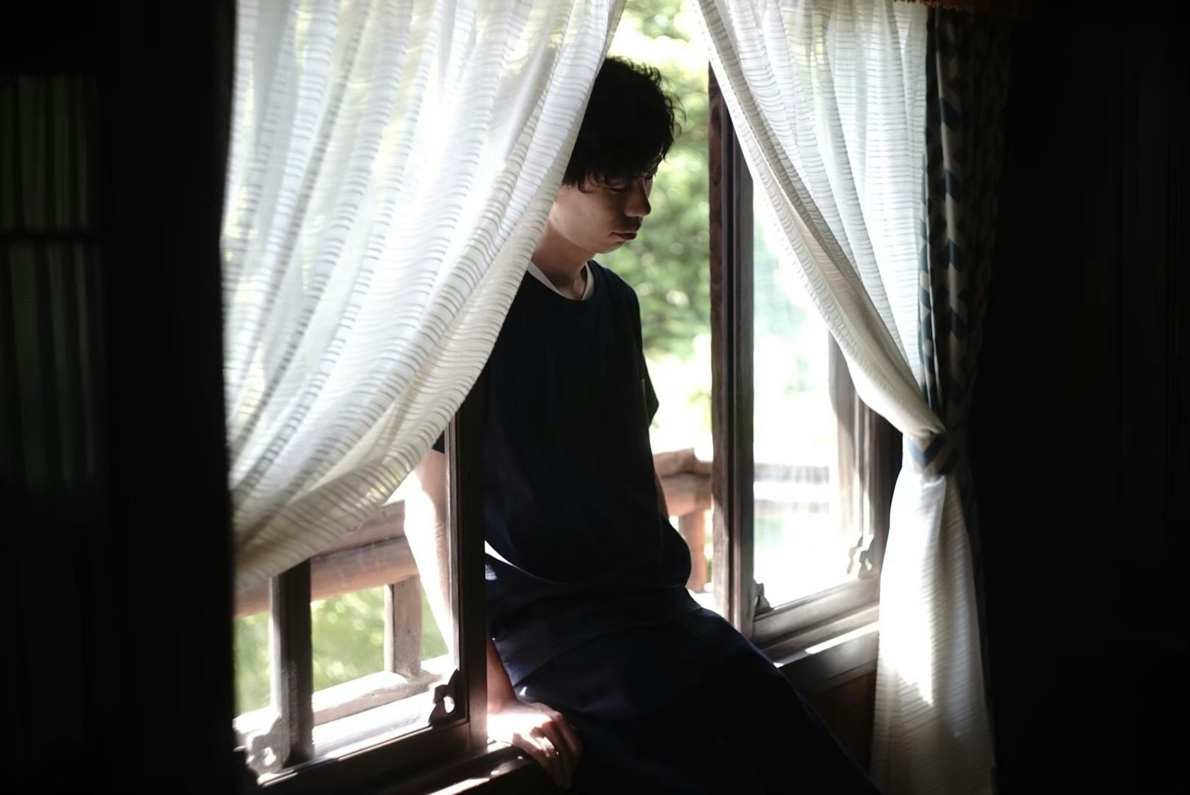 Silhouette of a man sitting by the window Soft light filtering through the curtains