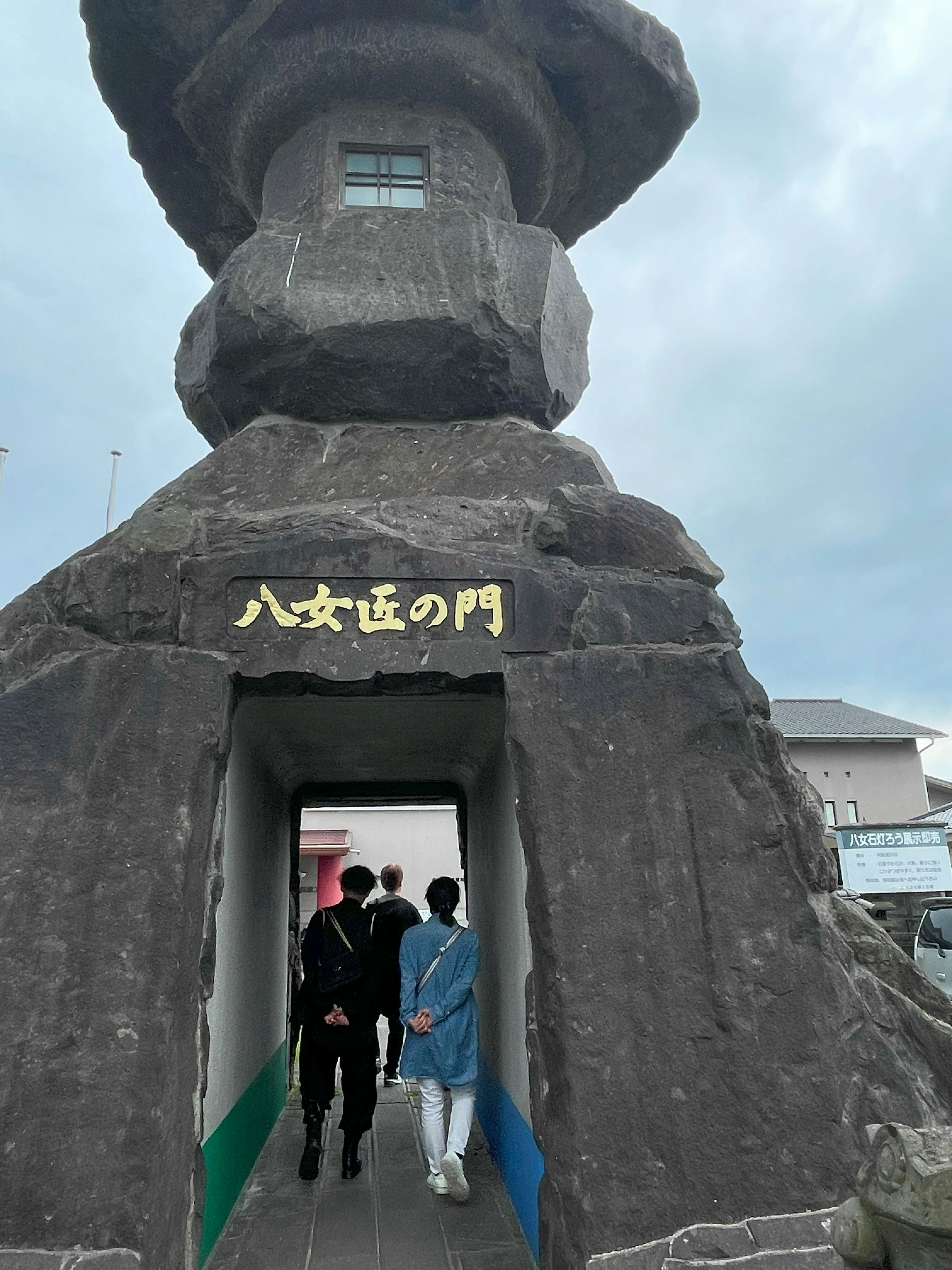 Menschen gehen durch eine Steinkonstruktion am Tor von Hachijo Island