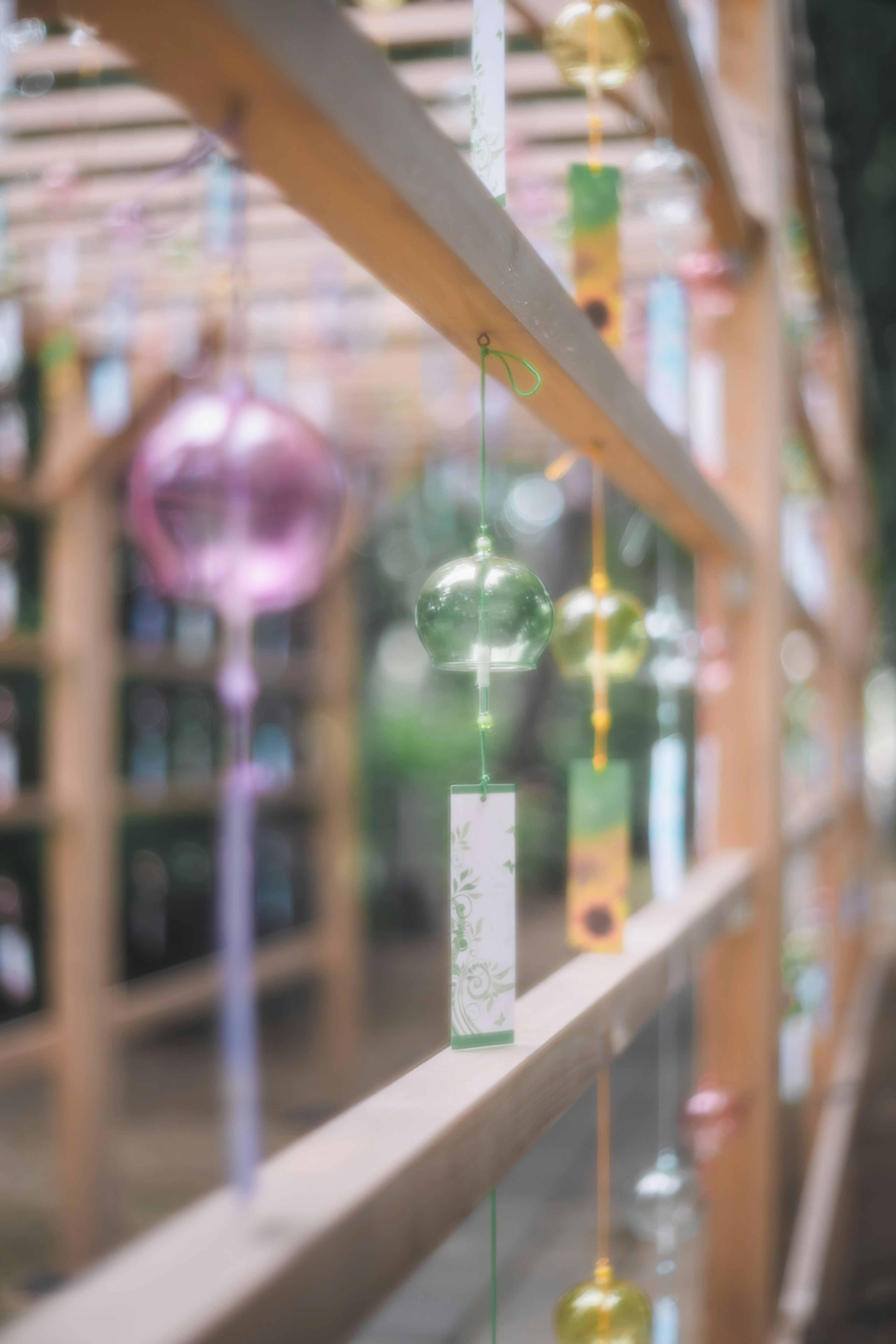 Gros plan de carillons suspendus à une structure en bois avec des carillons de couleur pastel