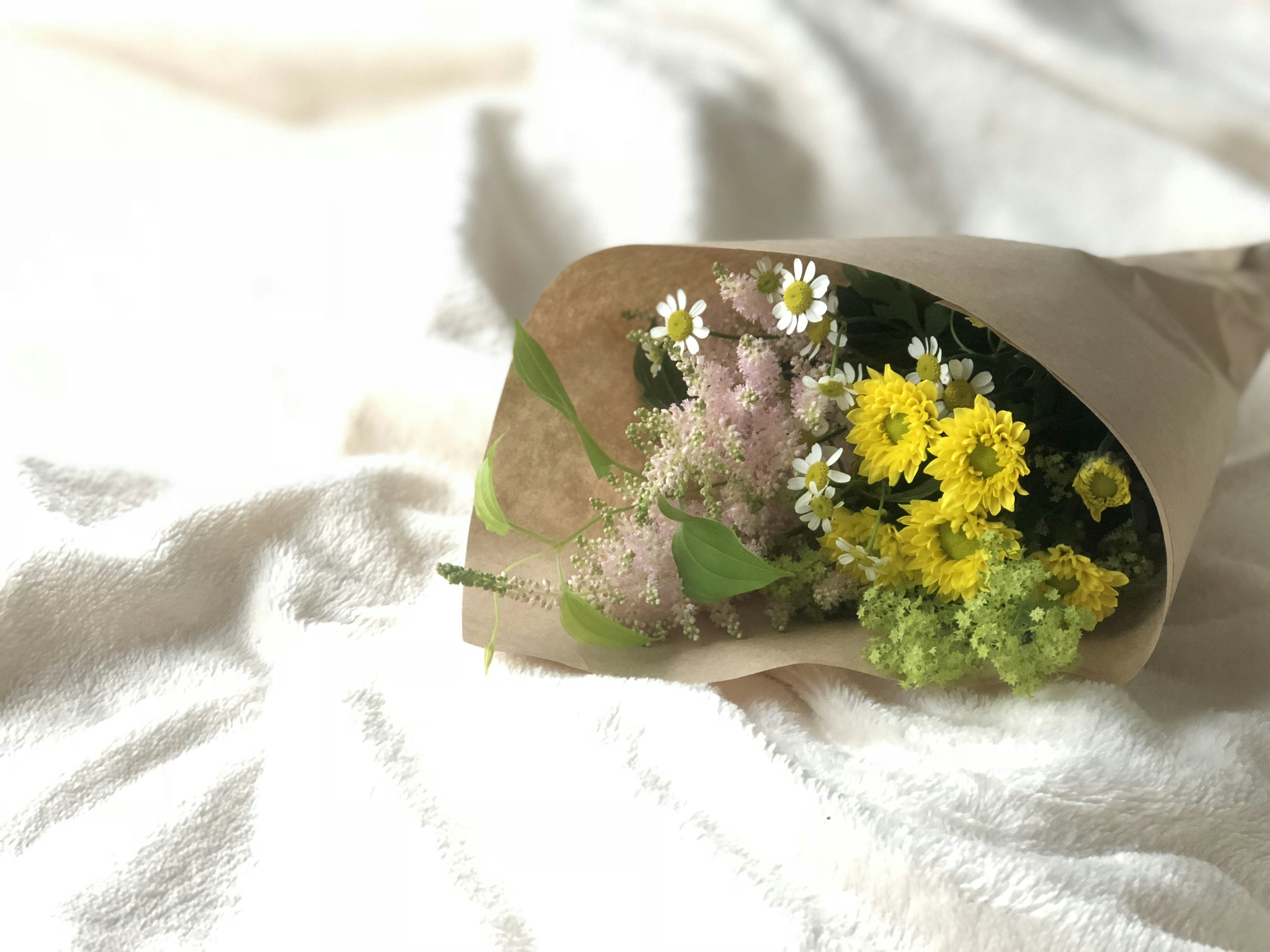 A bouquet of colorful flowers wrapped in brown paper