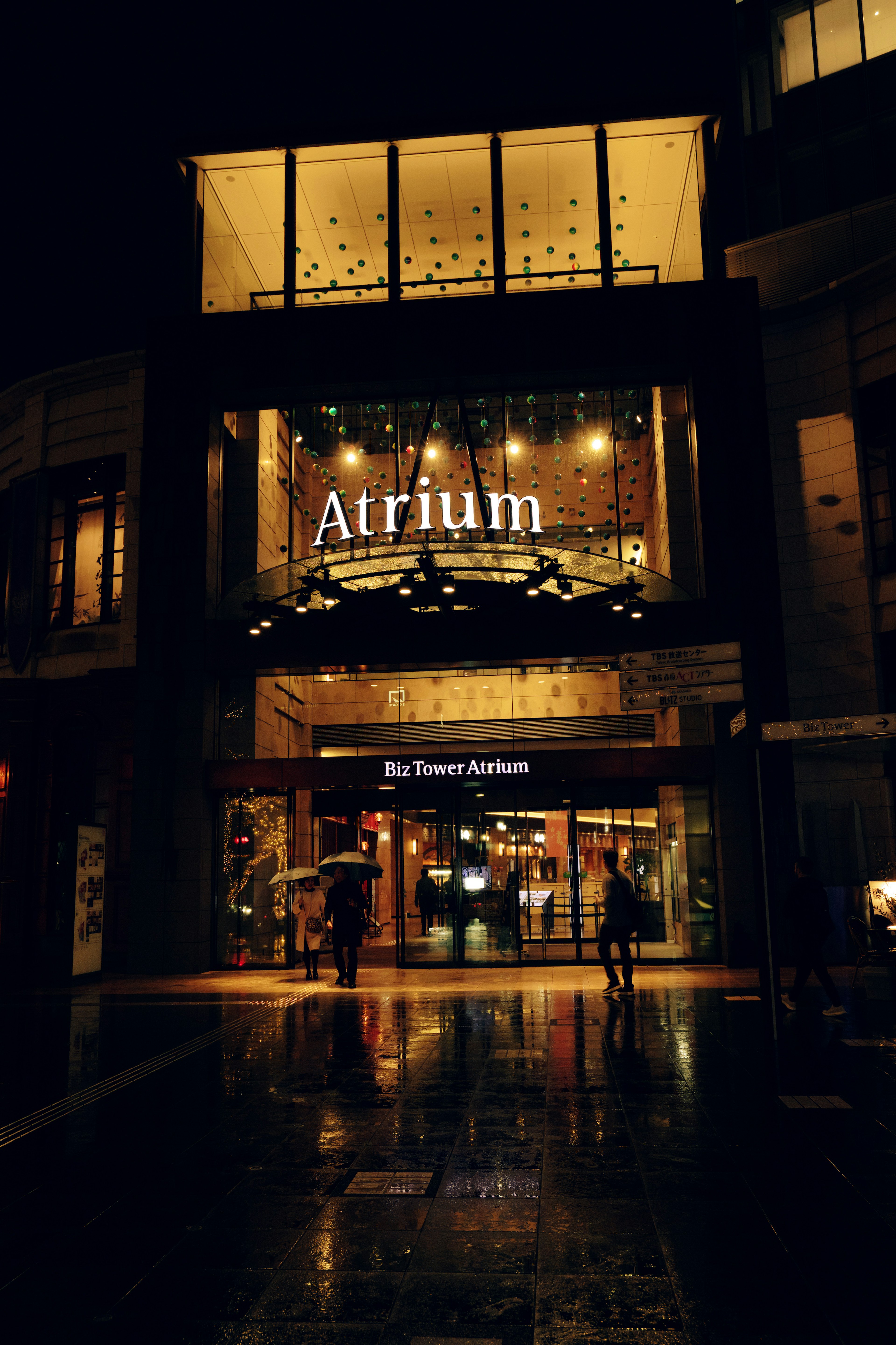 Außenansicht des Atriums bei Nacht helle Beschilderung und reflektierender Boden