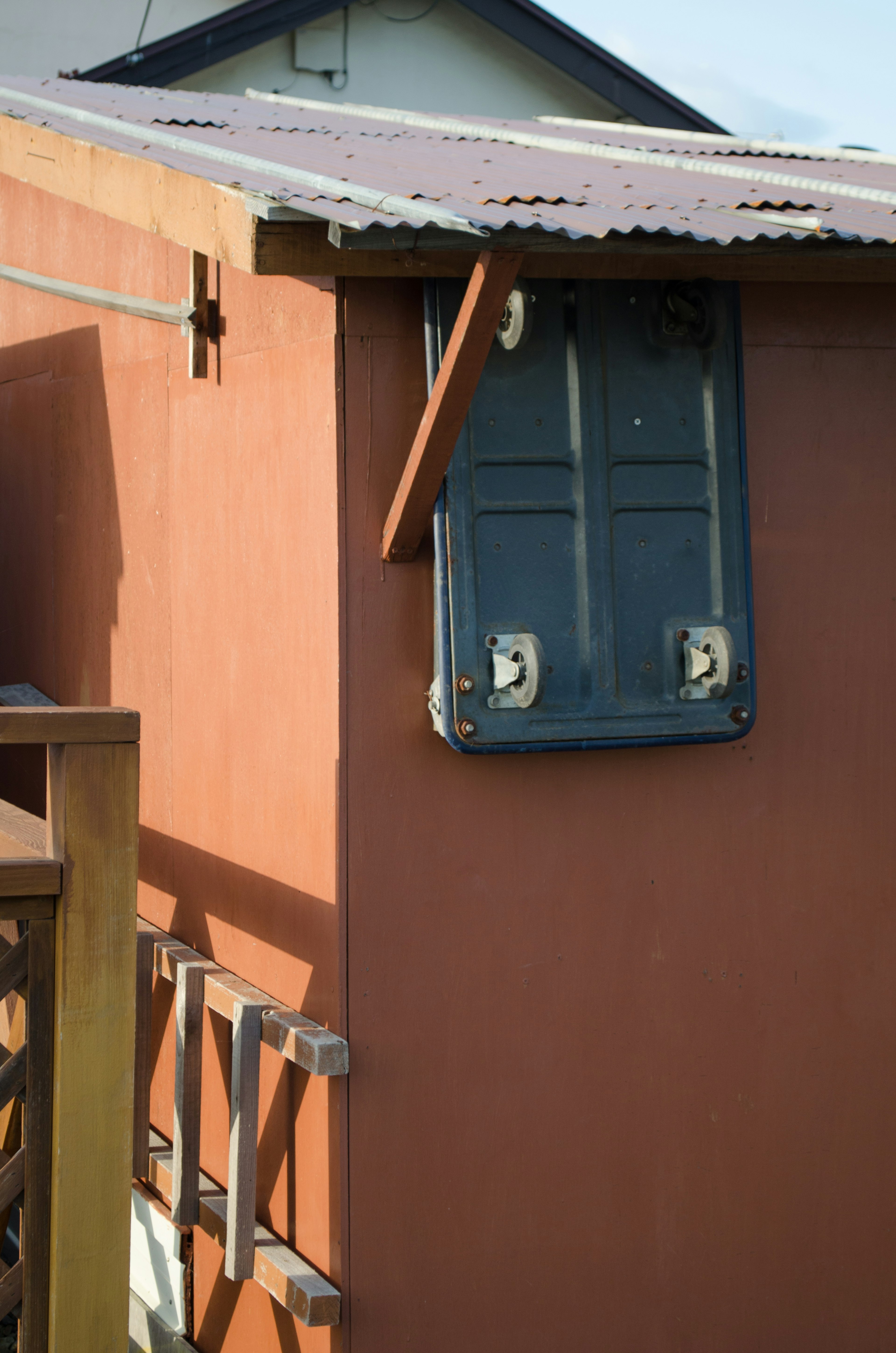 Part of a building featuring a blue window attached to a brown wall