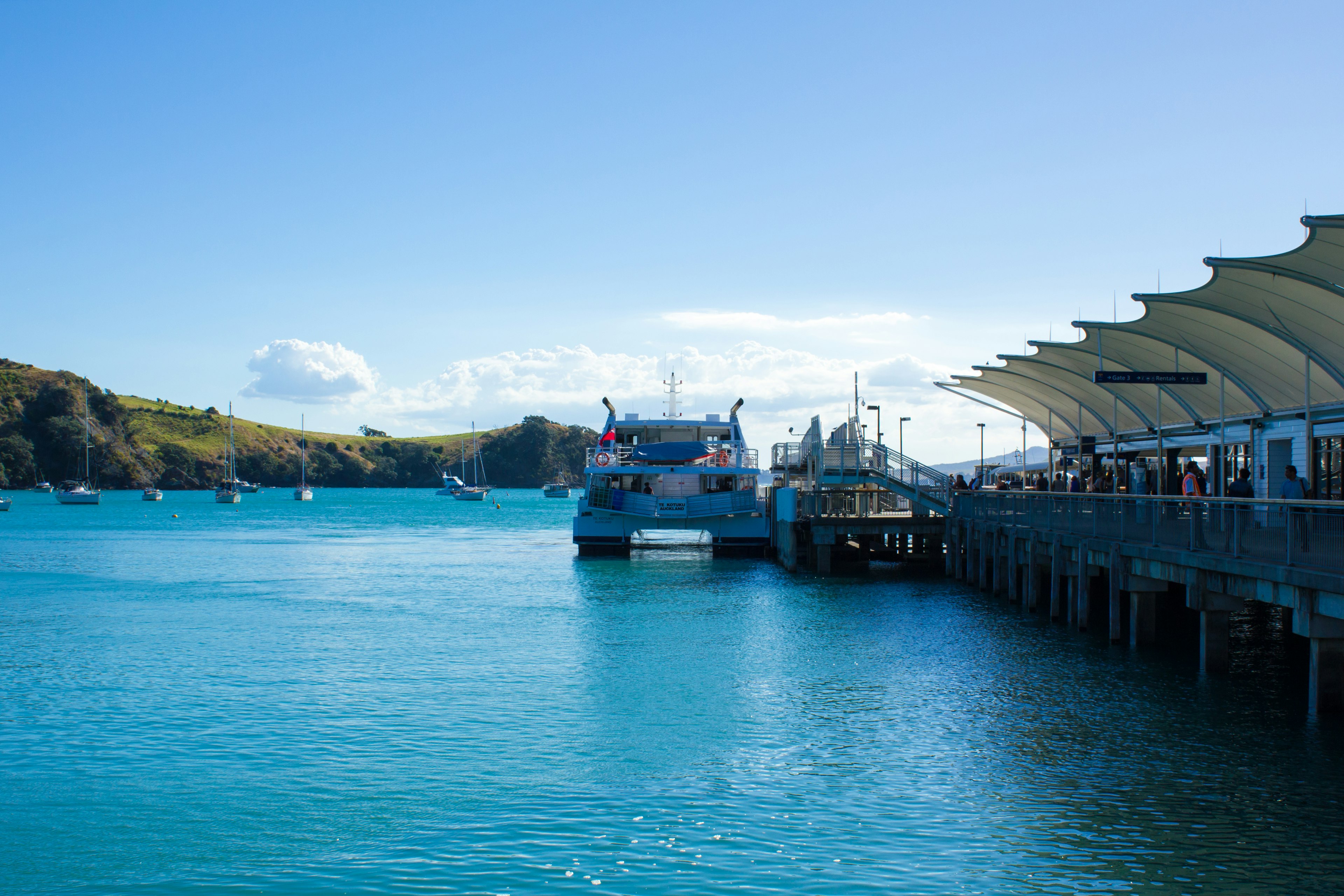 Malerei von einem blauen Meer mit einem Pier und angedockten Booten