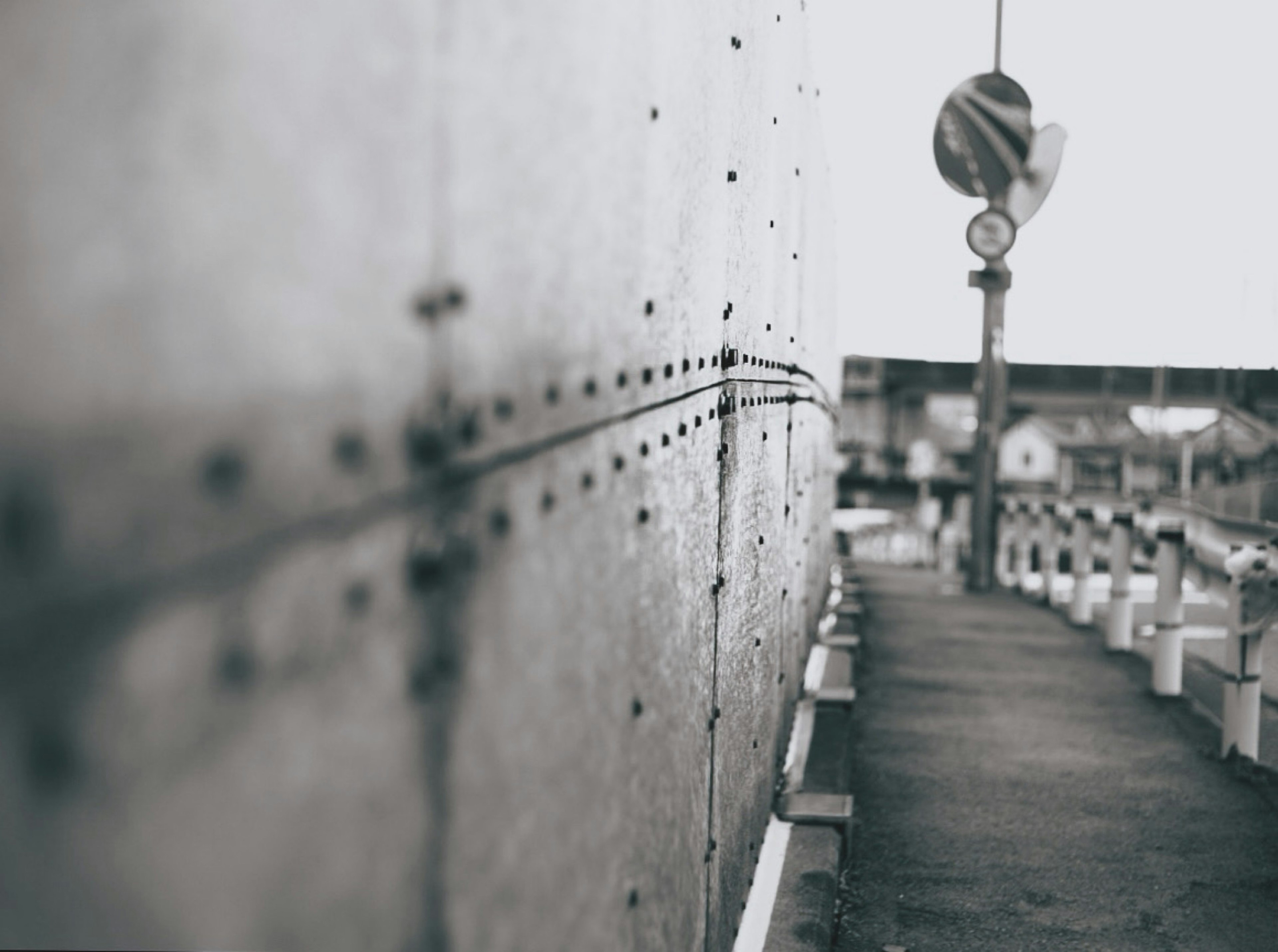 Monochrome scene featuring a metal wall and a pathway