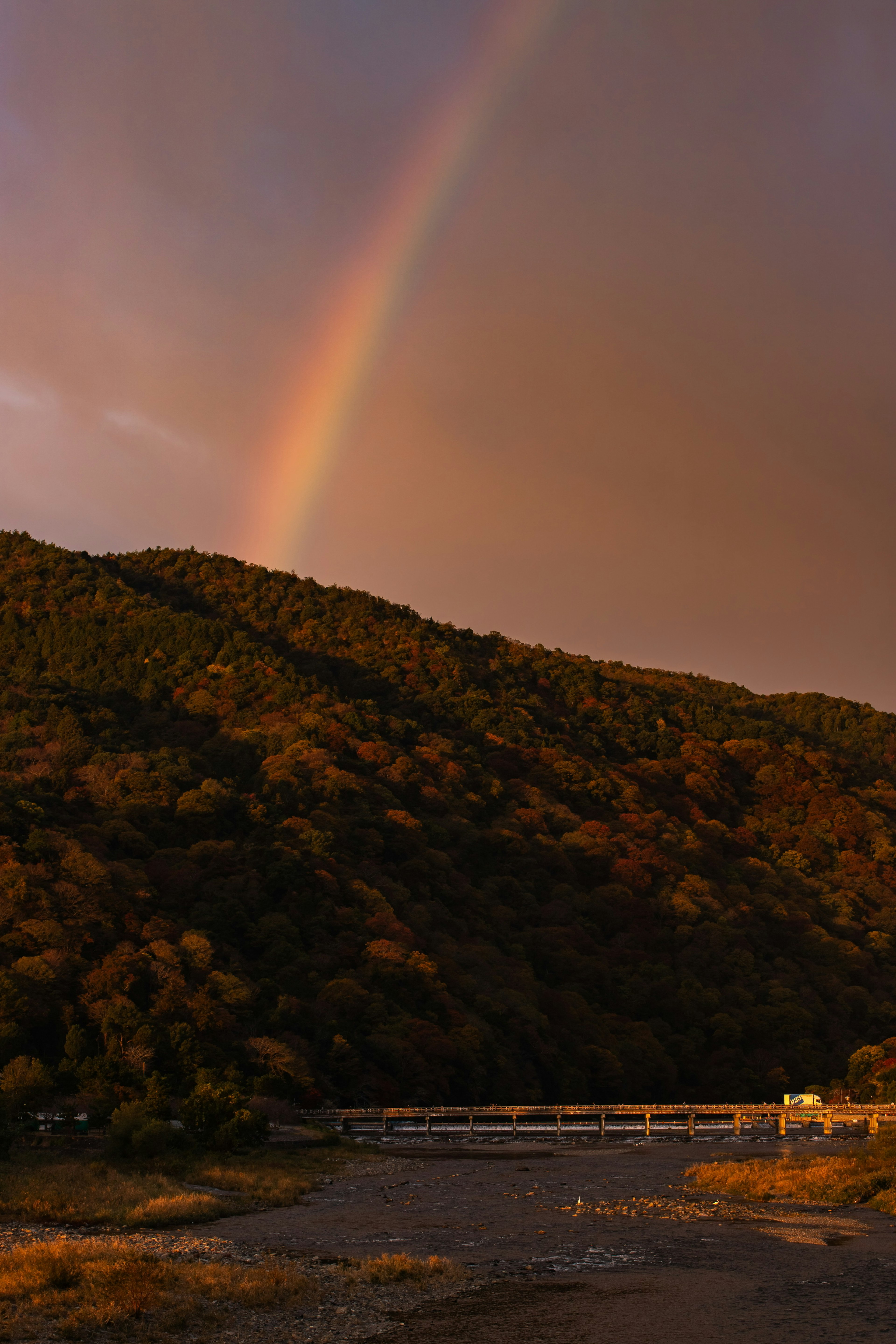 Un arc-en-ciel surplombant une montagne avec un ciel au coucher du soleil