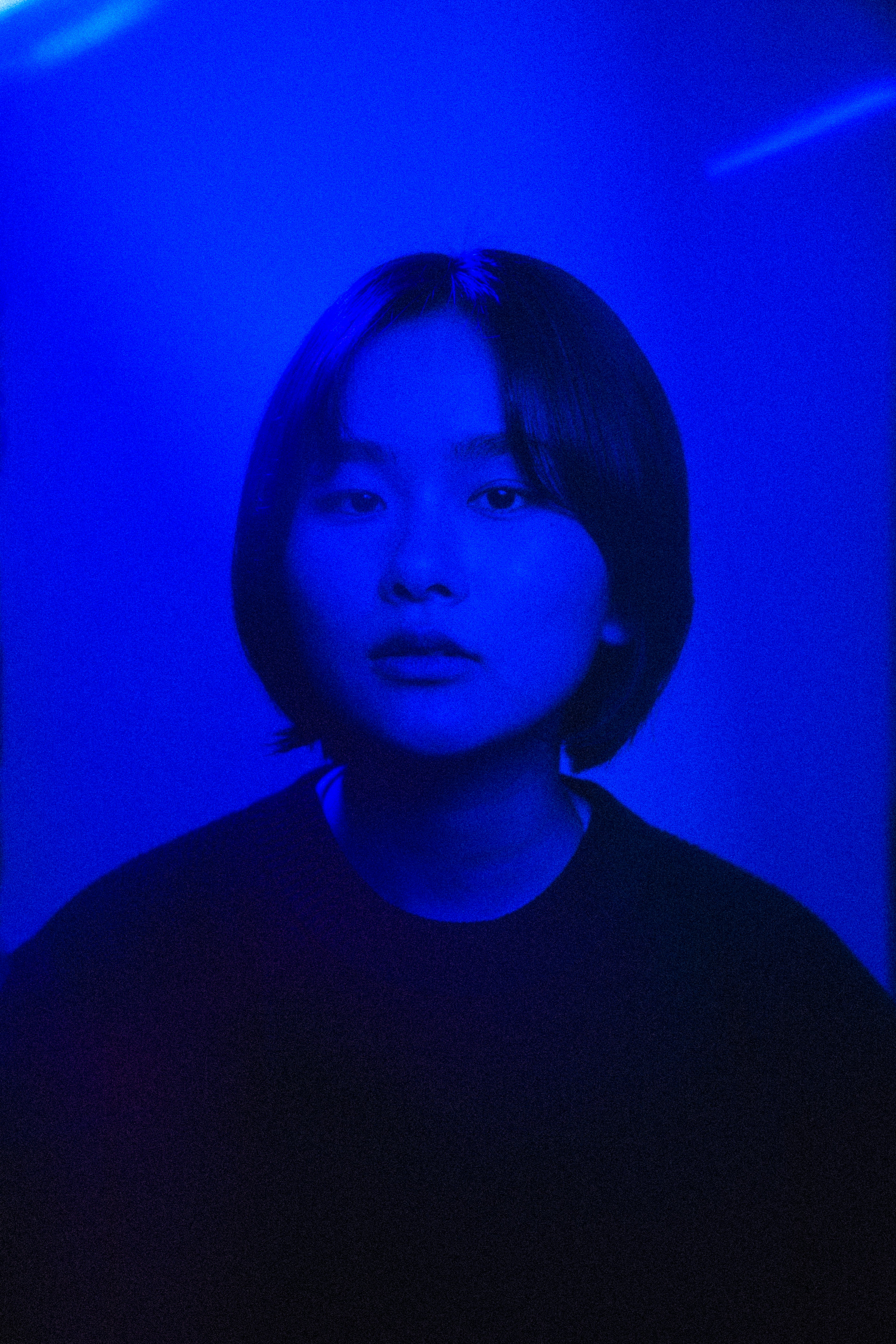 Portrait d'une personne aux cheveux courts éclairée par une lumière bleue