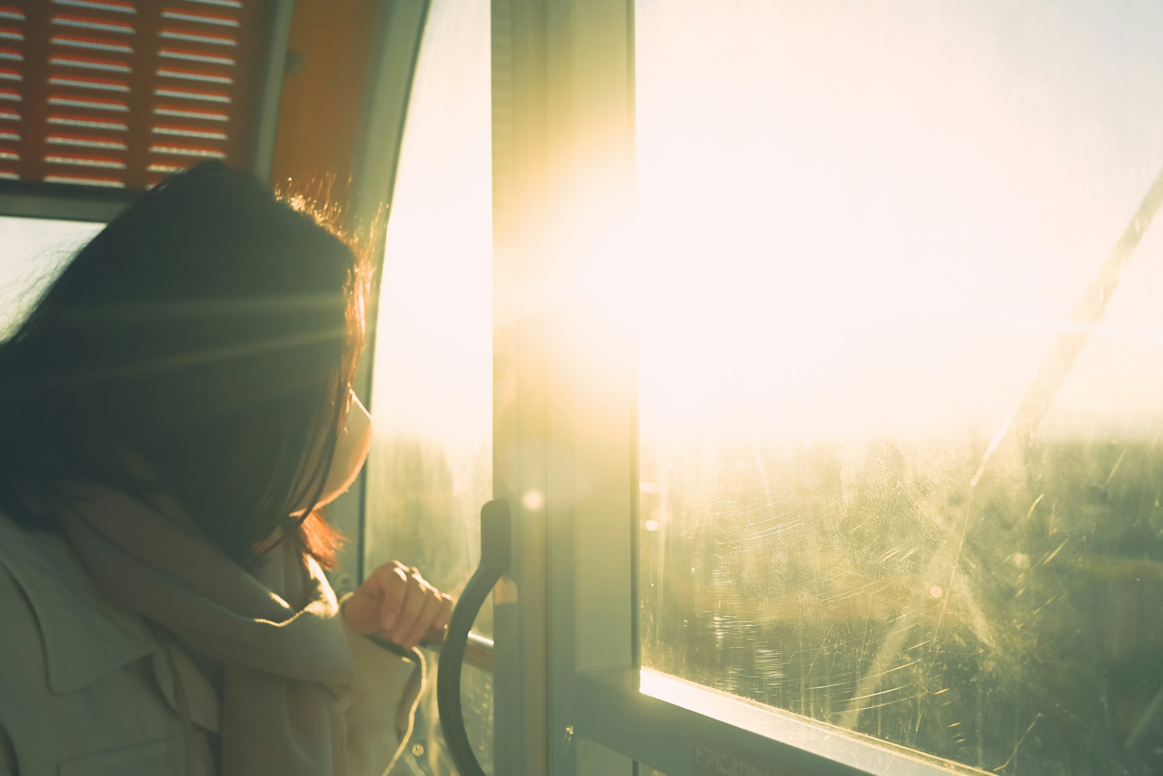 Frau, die aus dem Fenster schaut, während Sonnenlicht hereinfällt