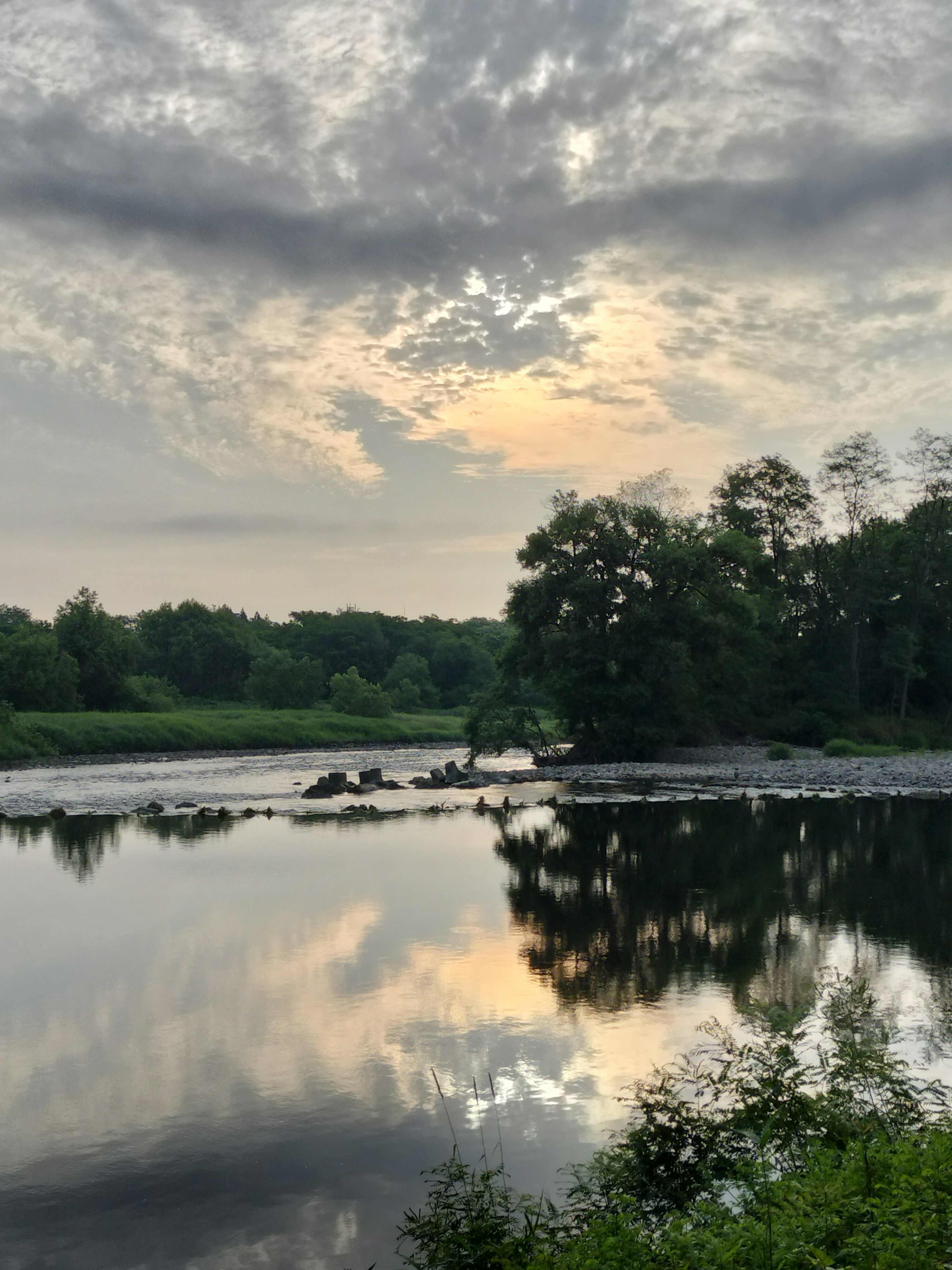 Ruhige Flusslandschaft mit Wolkenreflexionen und einem schönen Sonnenuntergangshimmel