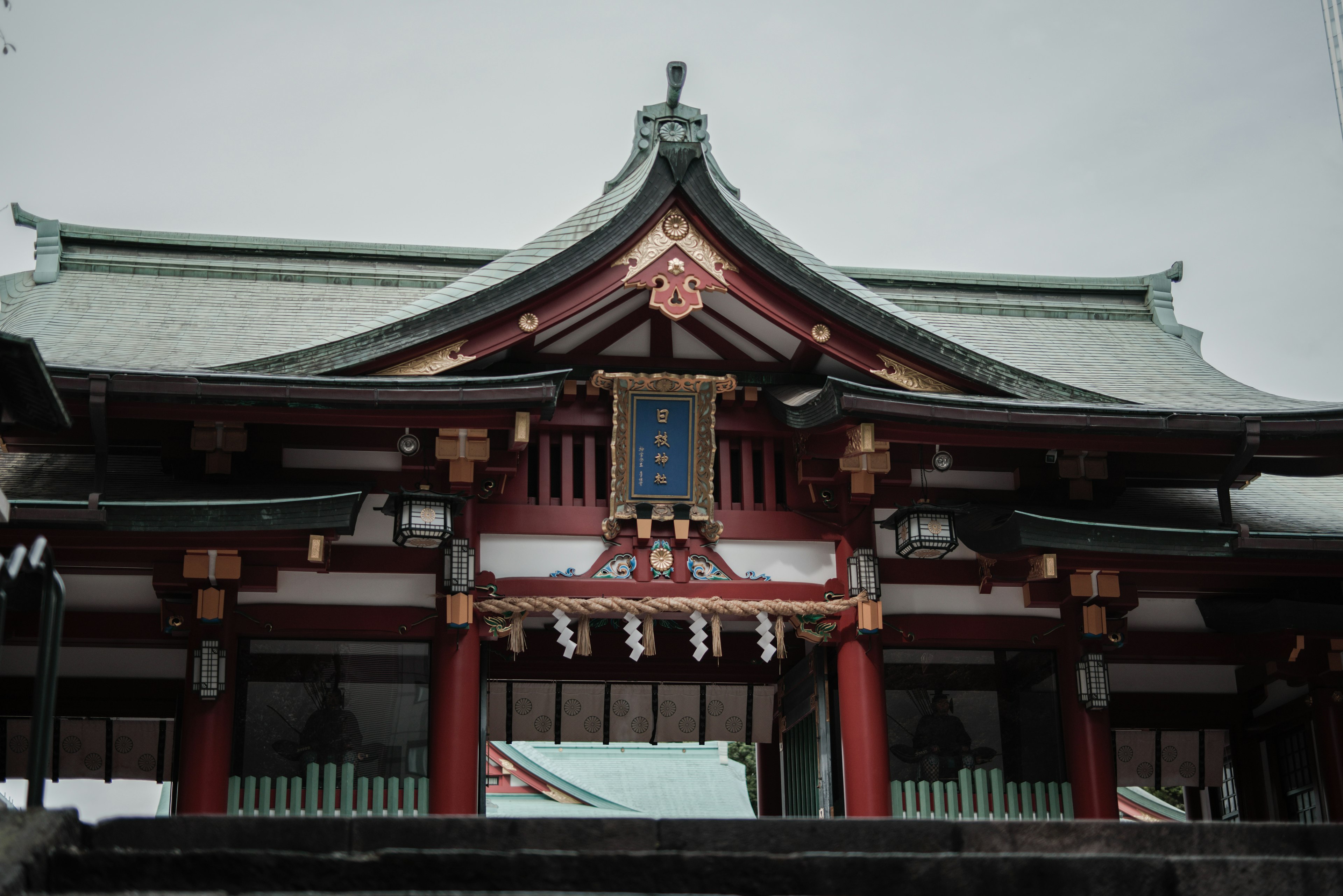 Traditional Japanese shrine architecture with red pillars and a green roof