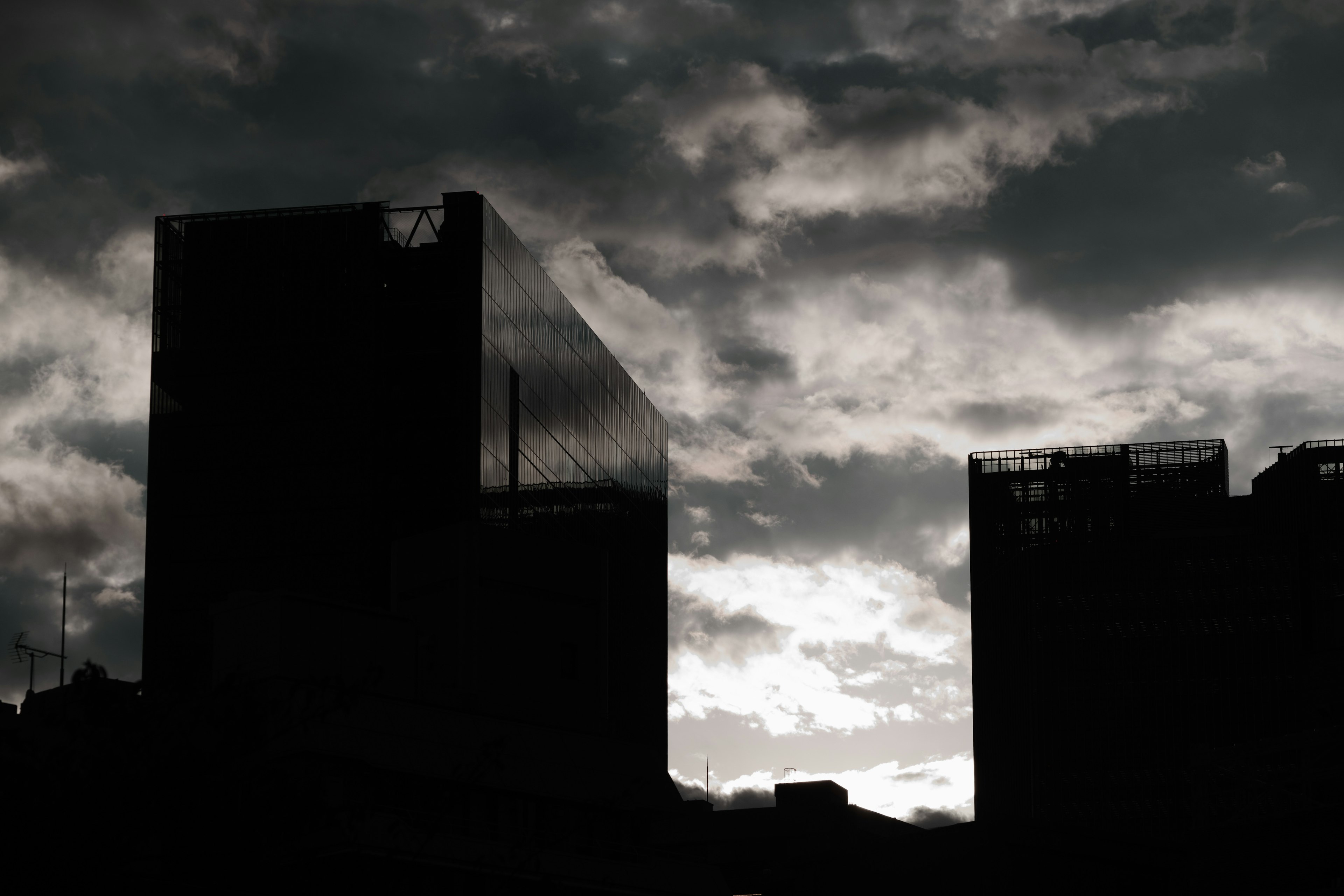 Silhouettes of skyscrapers against a dark cloudy sky