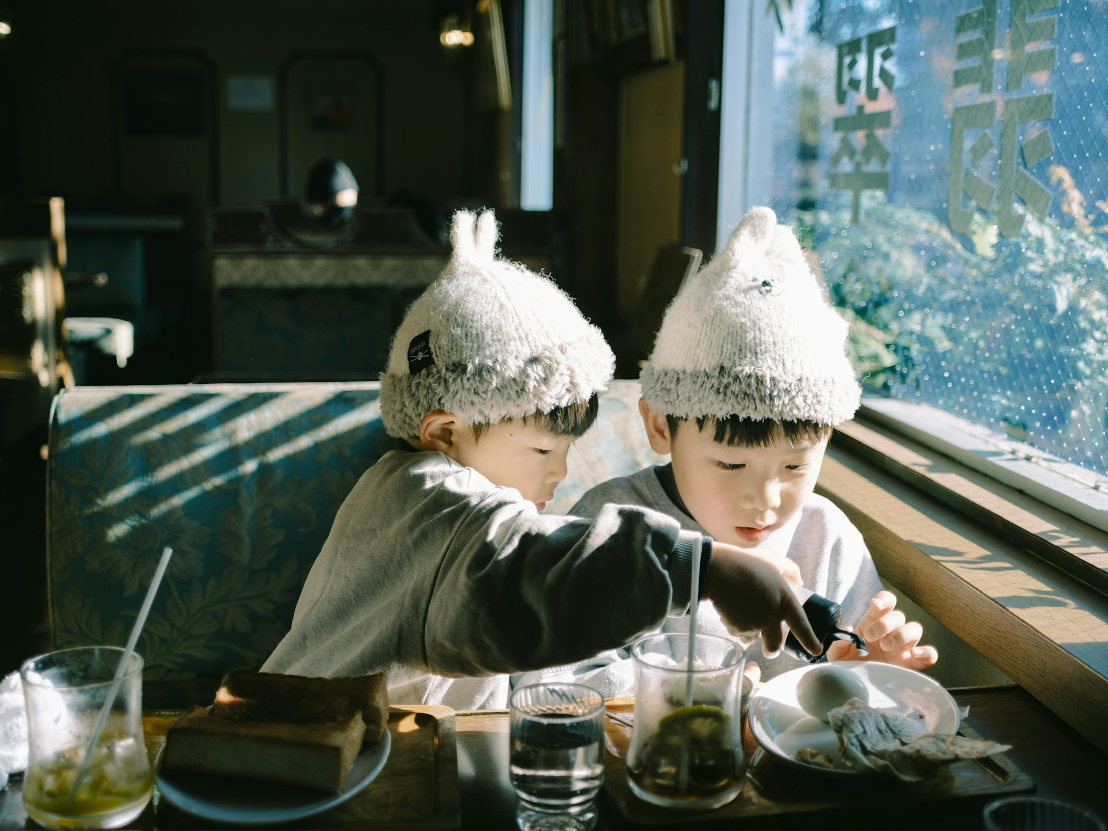 Two children enjoying a meal by the window