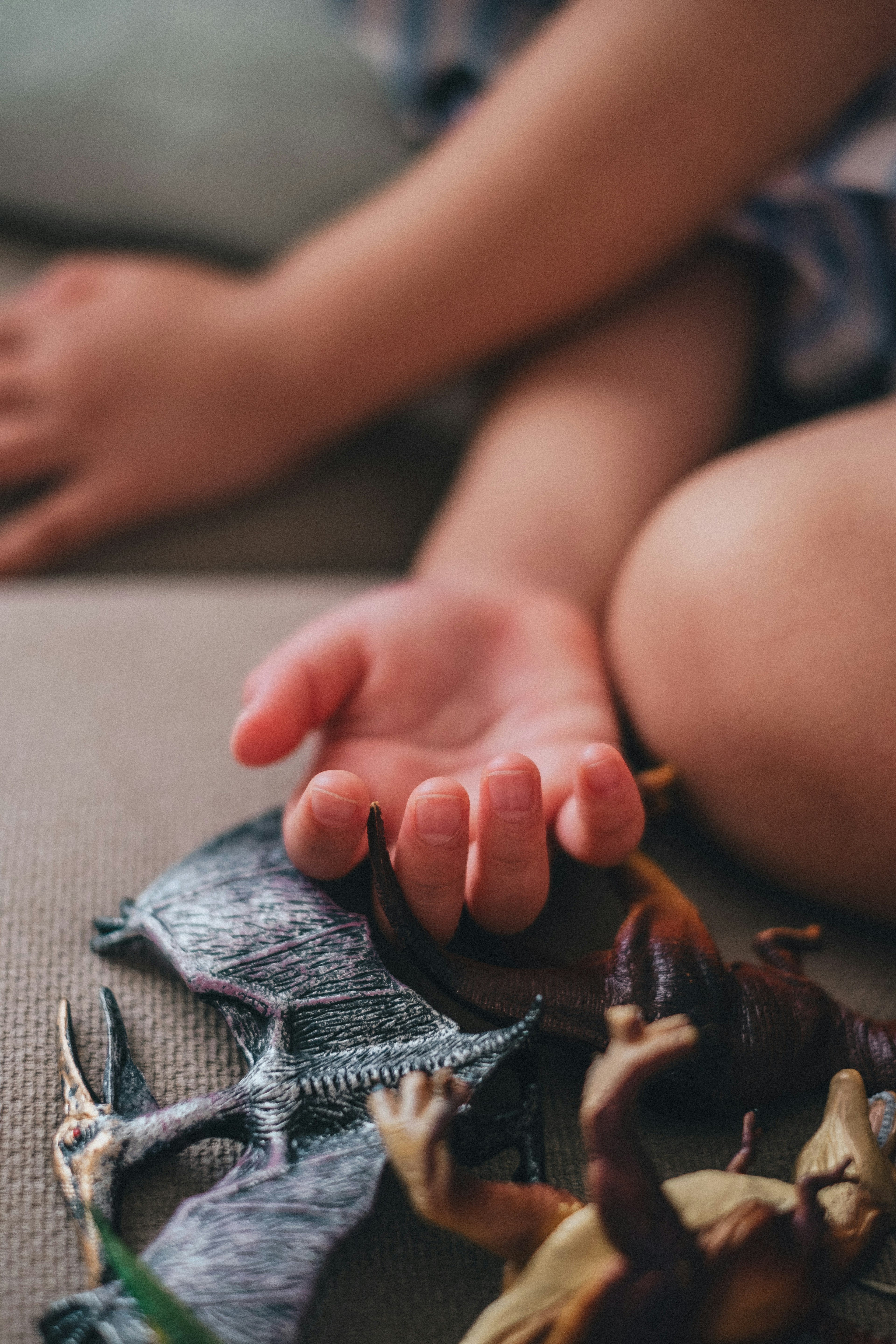 子供の手と恐竜のおもちゃが並んでいるシーン