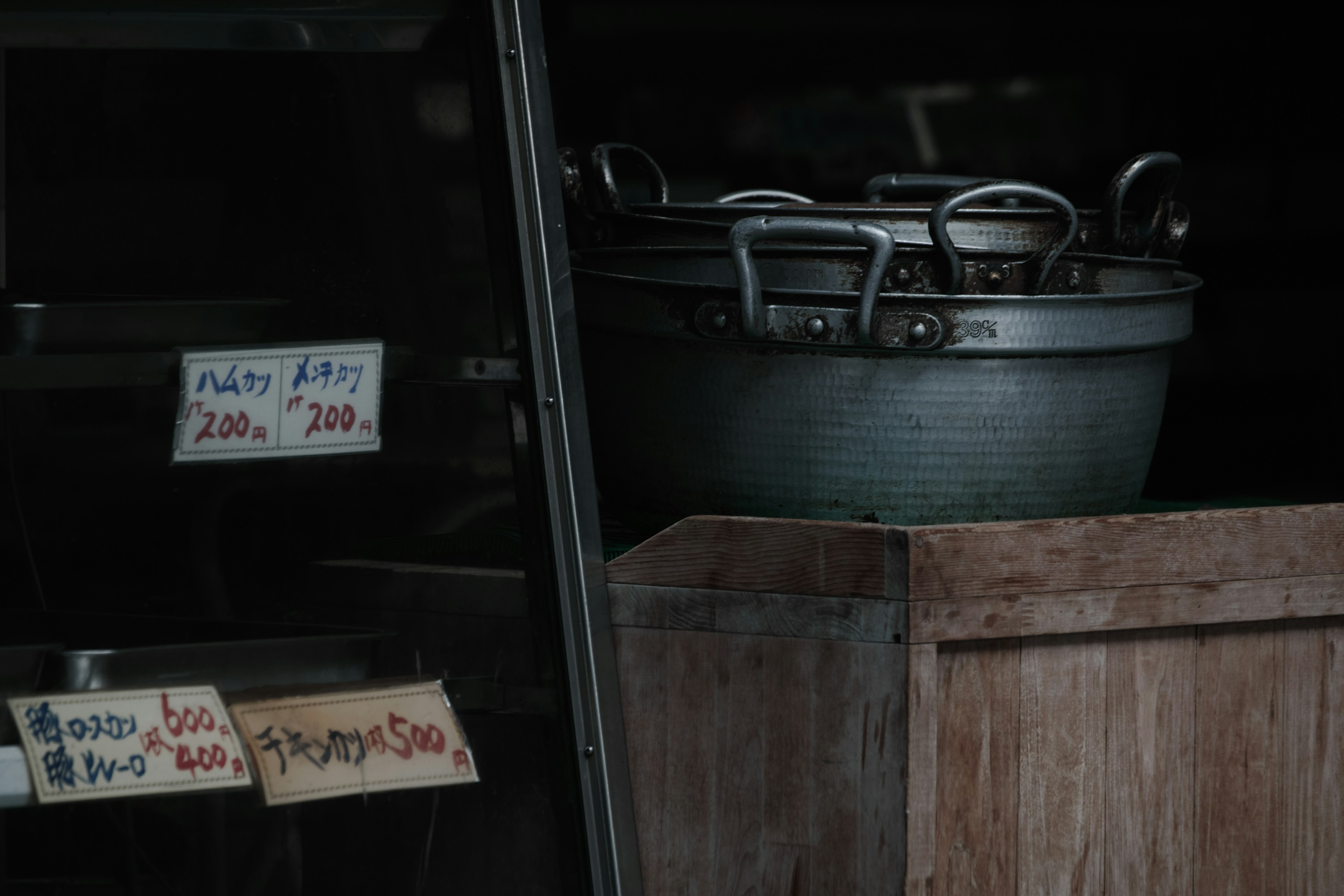 Interior oscuro de una tienda con una caja de madera y una olla