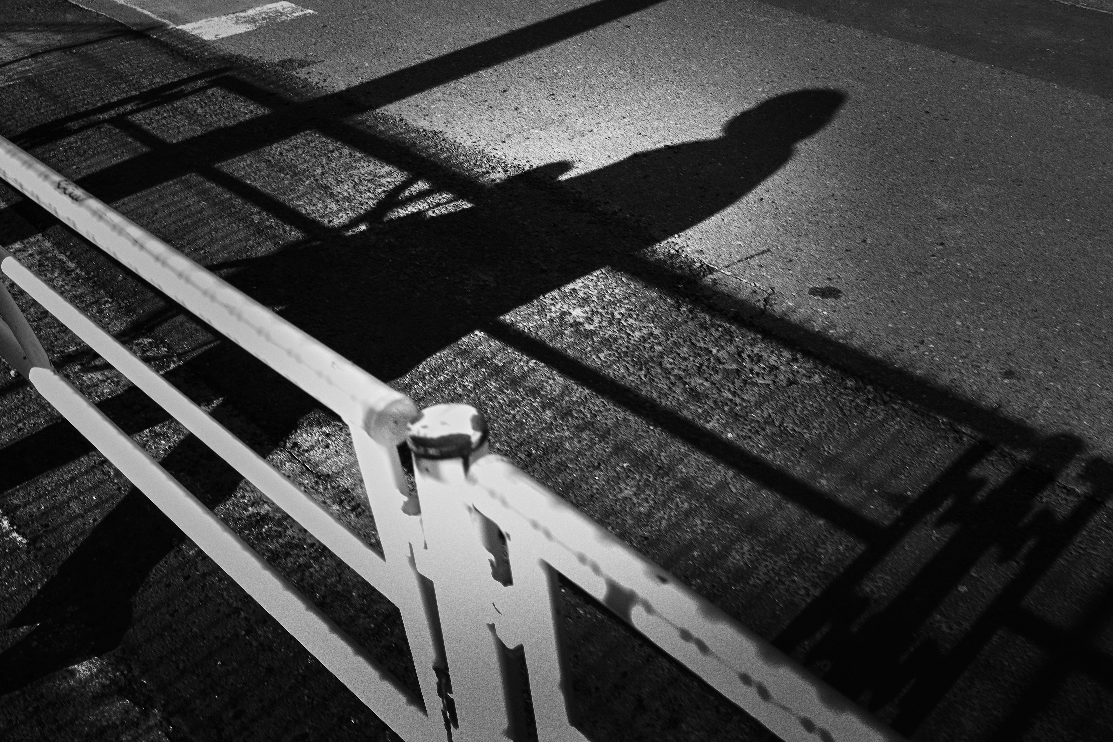 Silhouette of a person walking in front of a fence in black and white