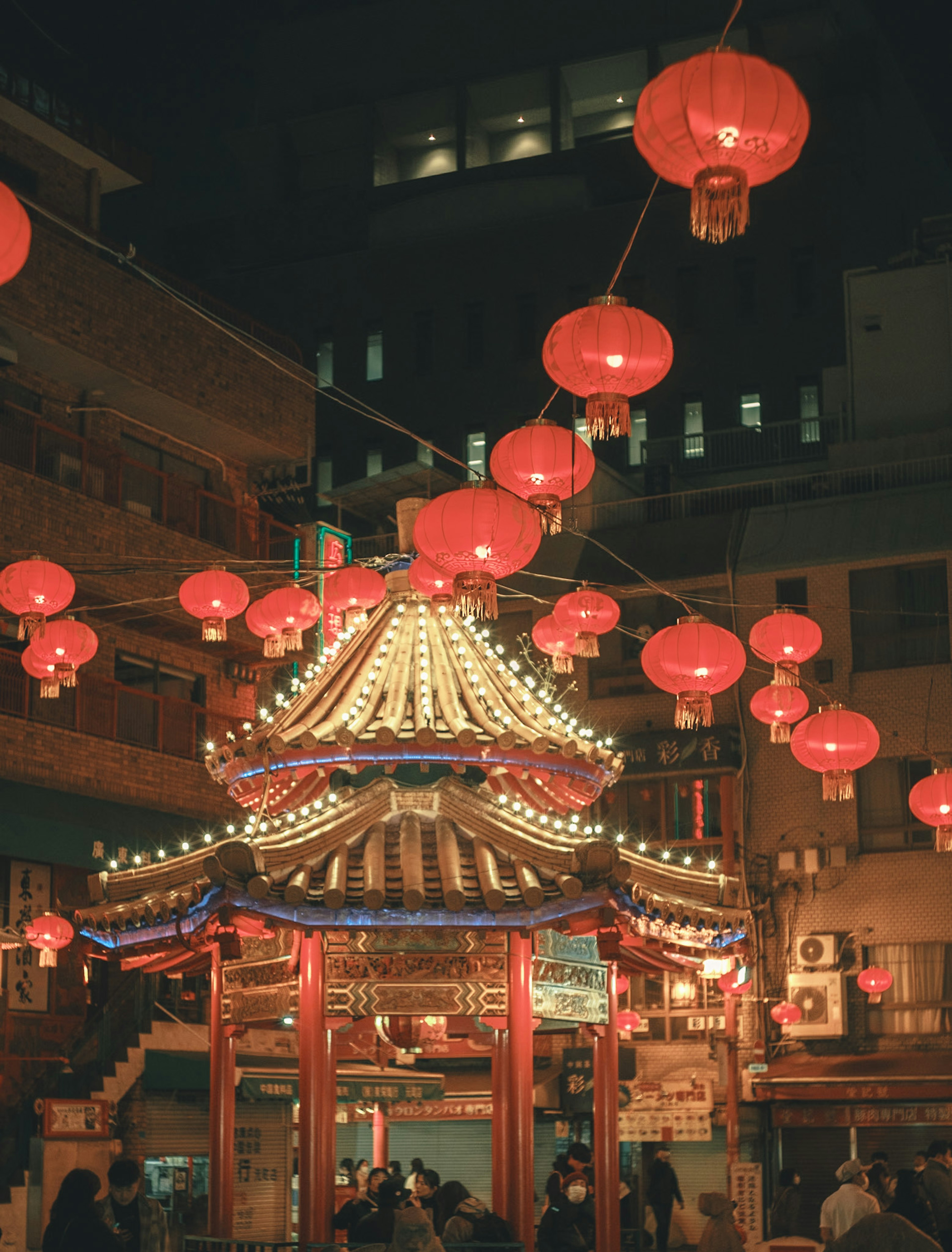 Traditionelles chinesisches Pavillon geschmückt mit roten Laternen in einer nächtlichen Stadtlandschaft