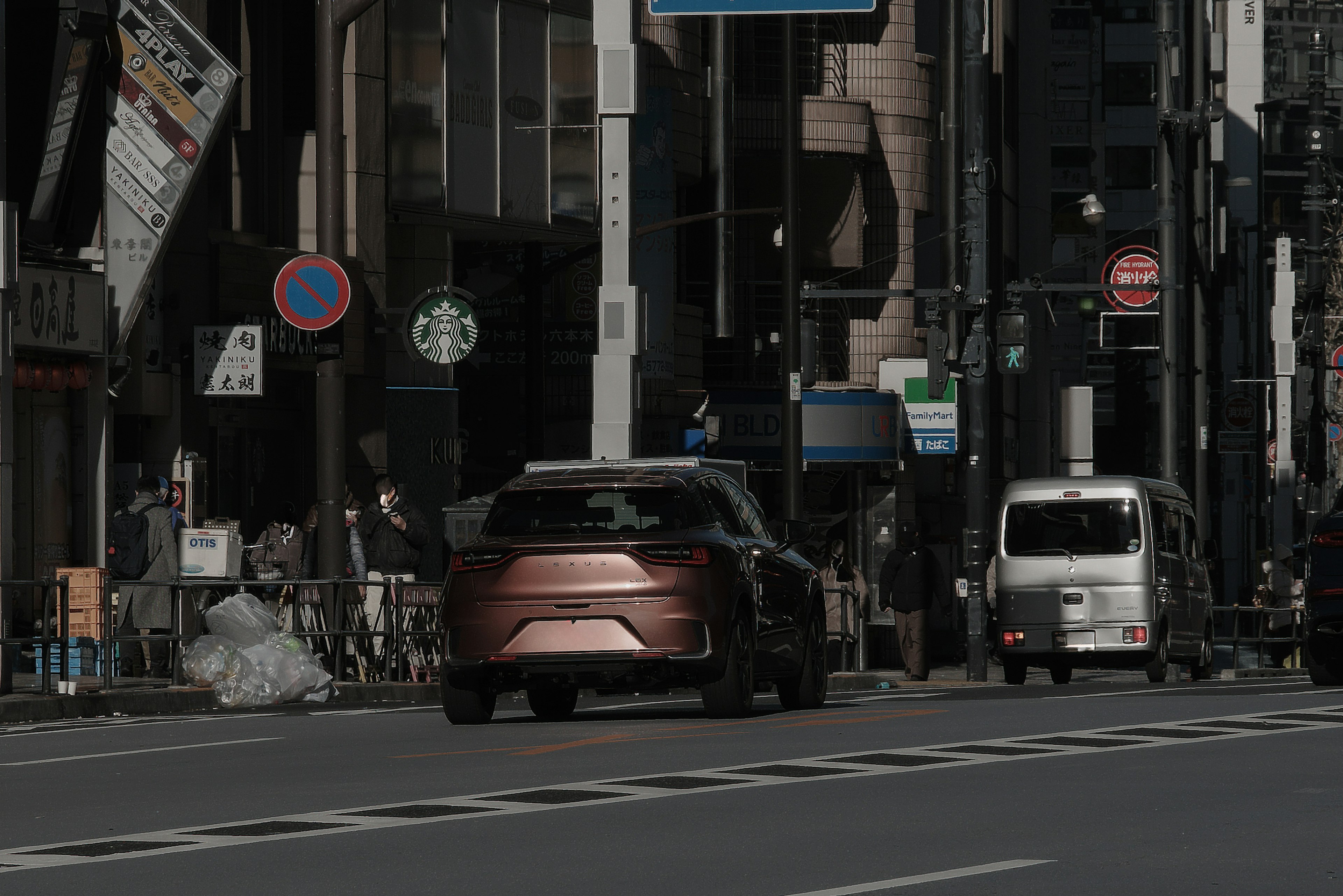 Une vue d'une rue de la ville avec une voiture rouge et un petit véhicule blanc