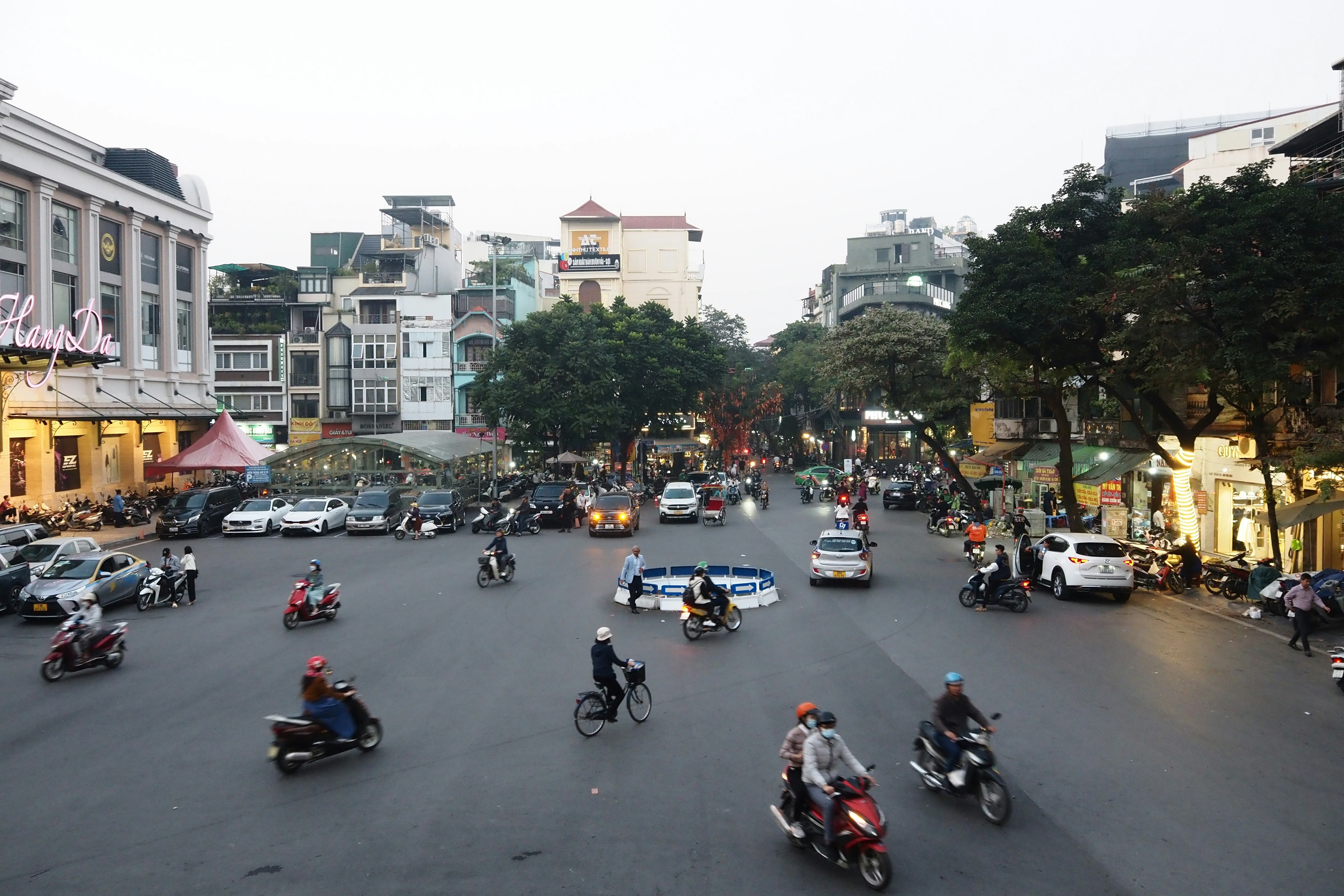 สี่แยกที่มีคนพลุกพล่านในฮานอยมีมอเตอร์ไซค์และรถยนต์จำนวนมากในช่วงเย็น