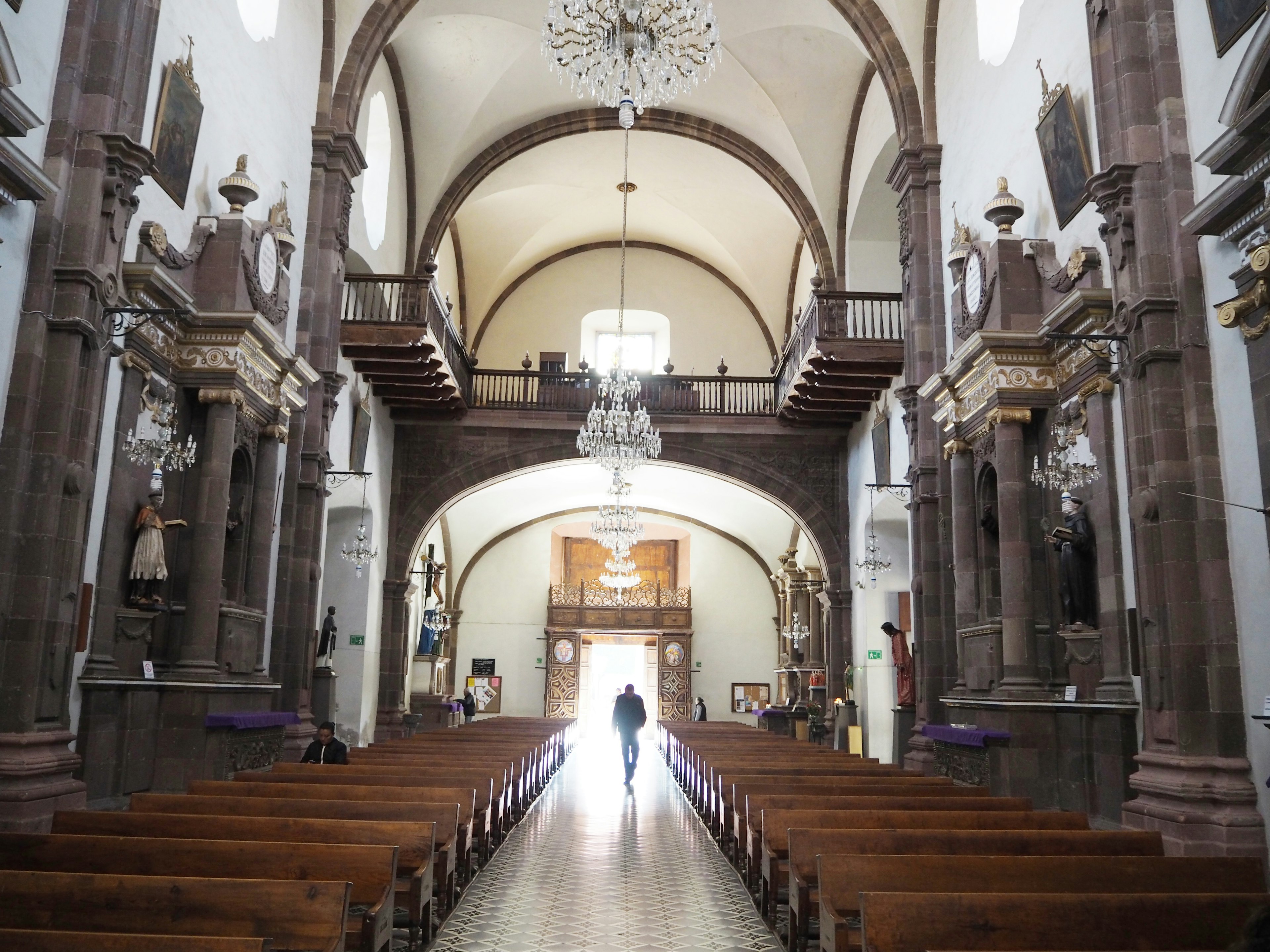 Interior of a church with a long aisle wooden benches chandelier bright light coming through