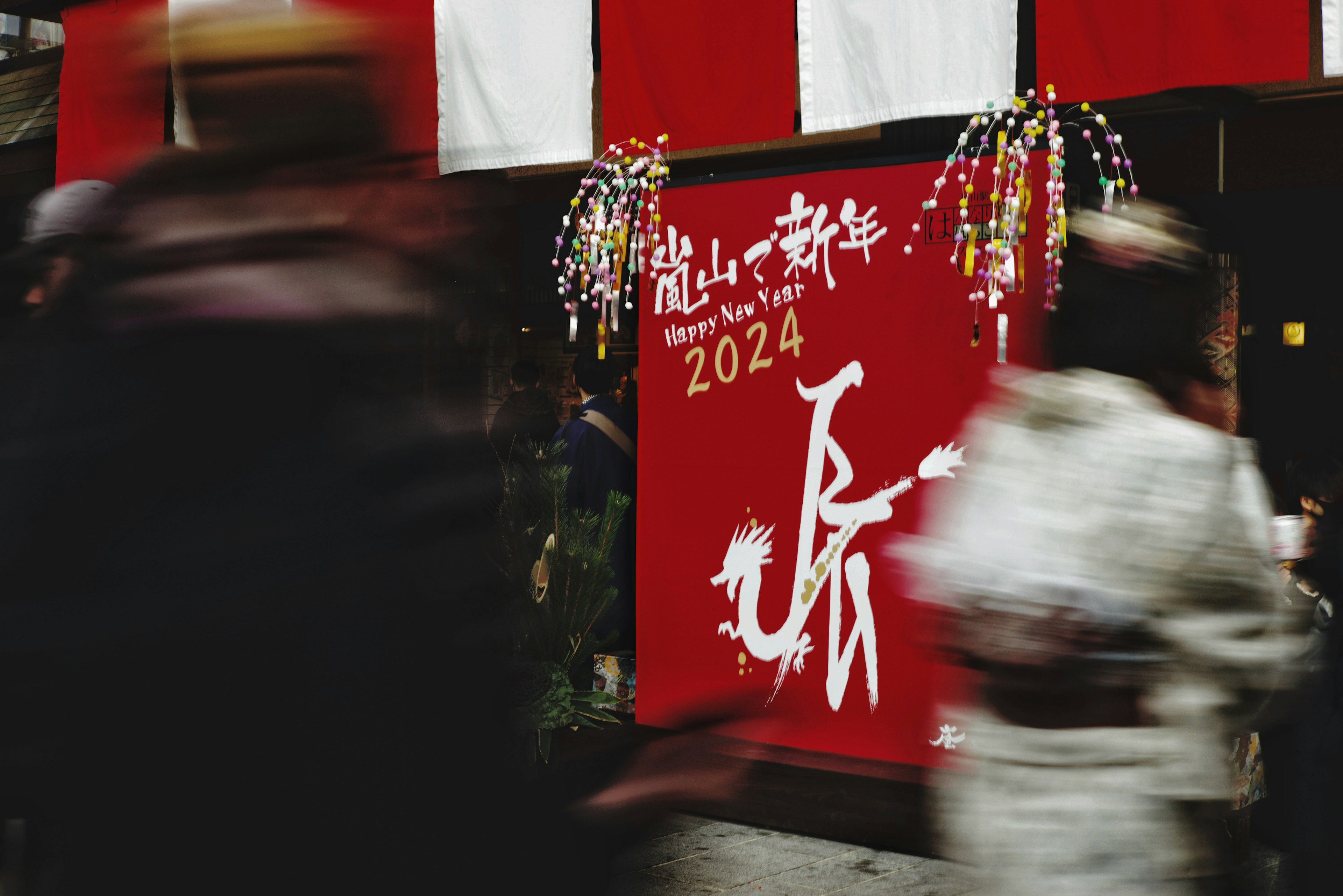 Red background with white New Year decoration featuring 2024 people passing by