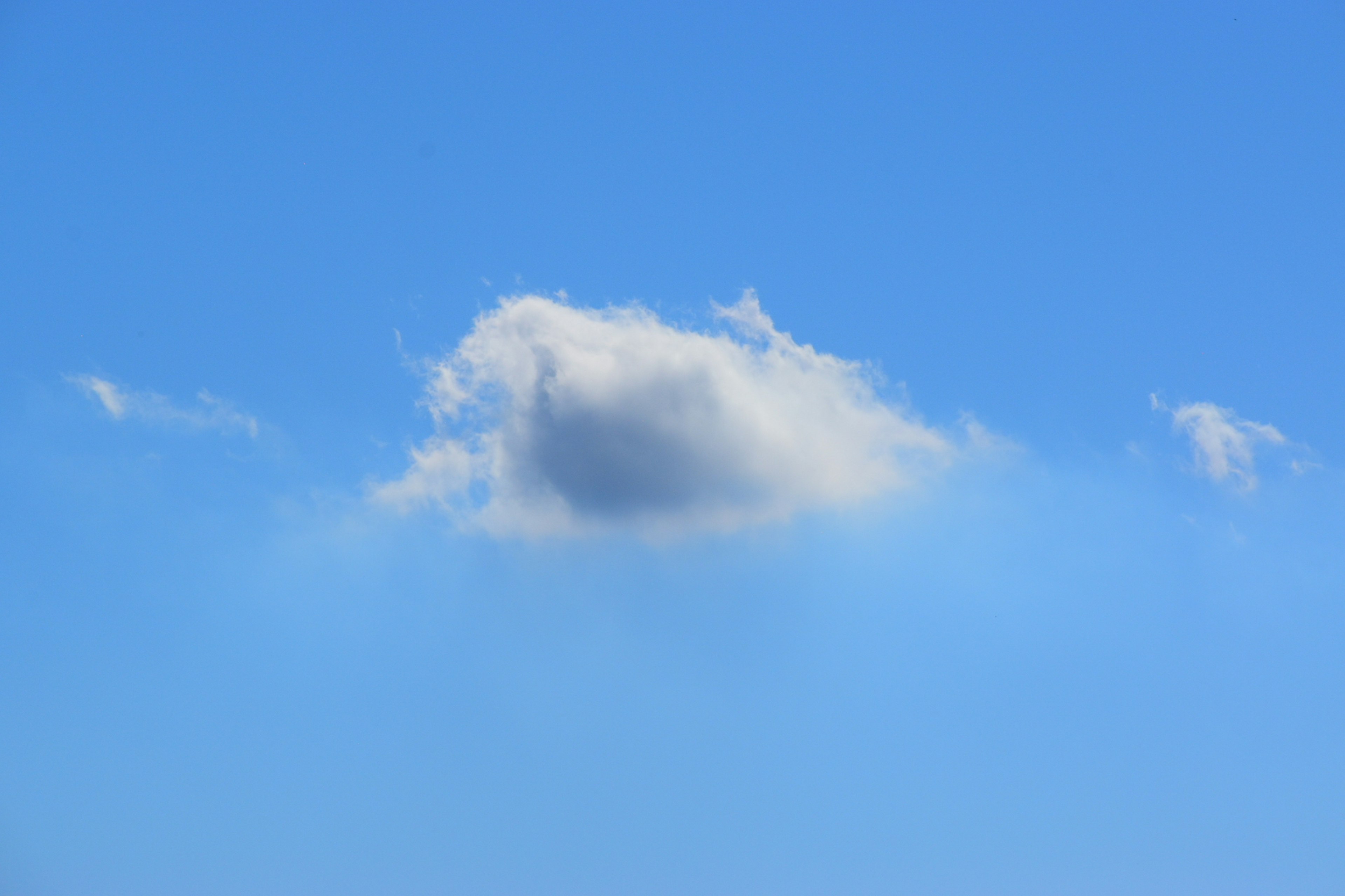 Un paisaje simple de una nube blanca flotando en un cielo azul