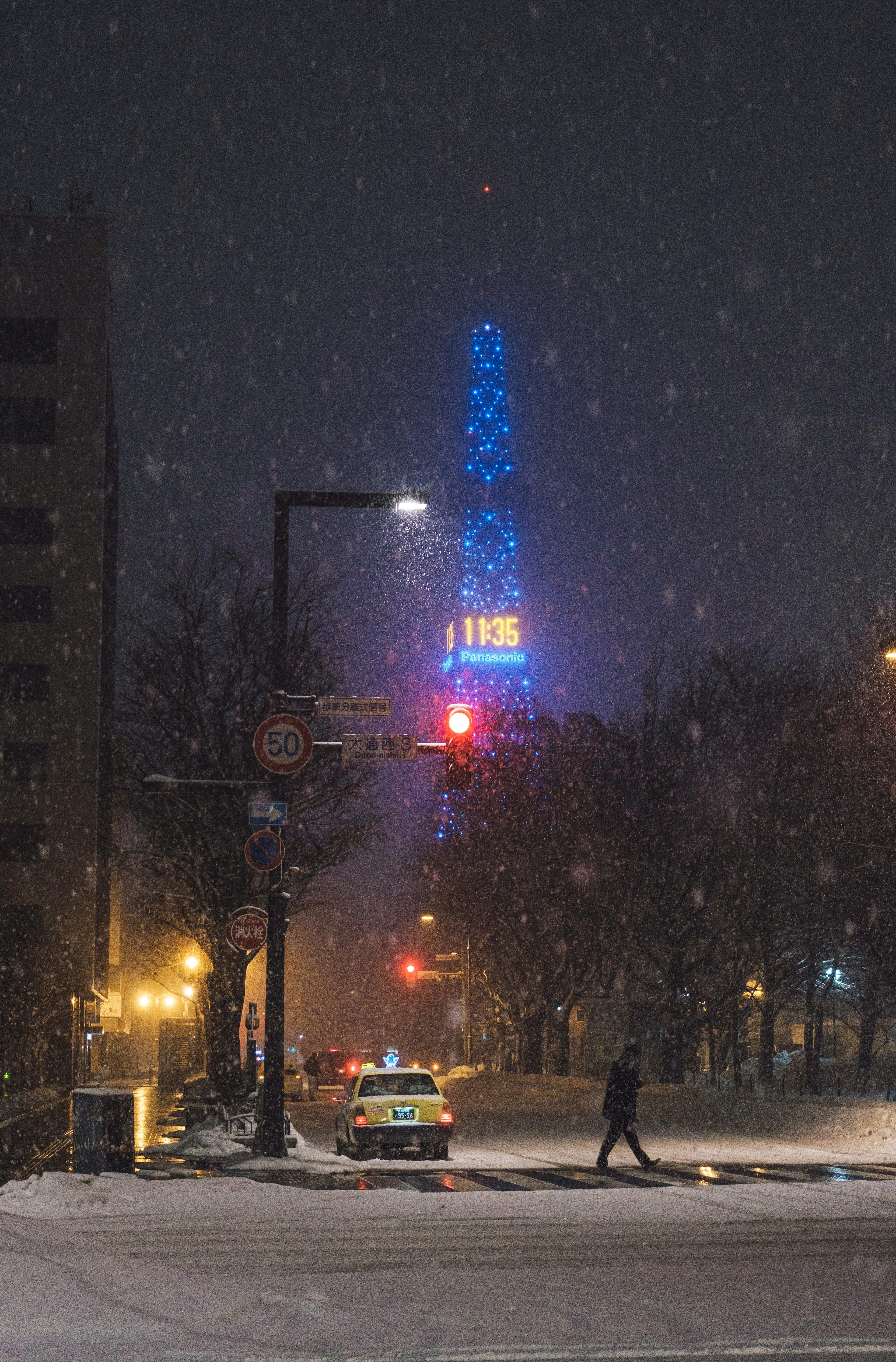 Nighttime city scene with a blue tower illuminated in the snow