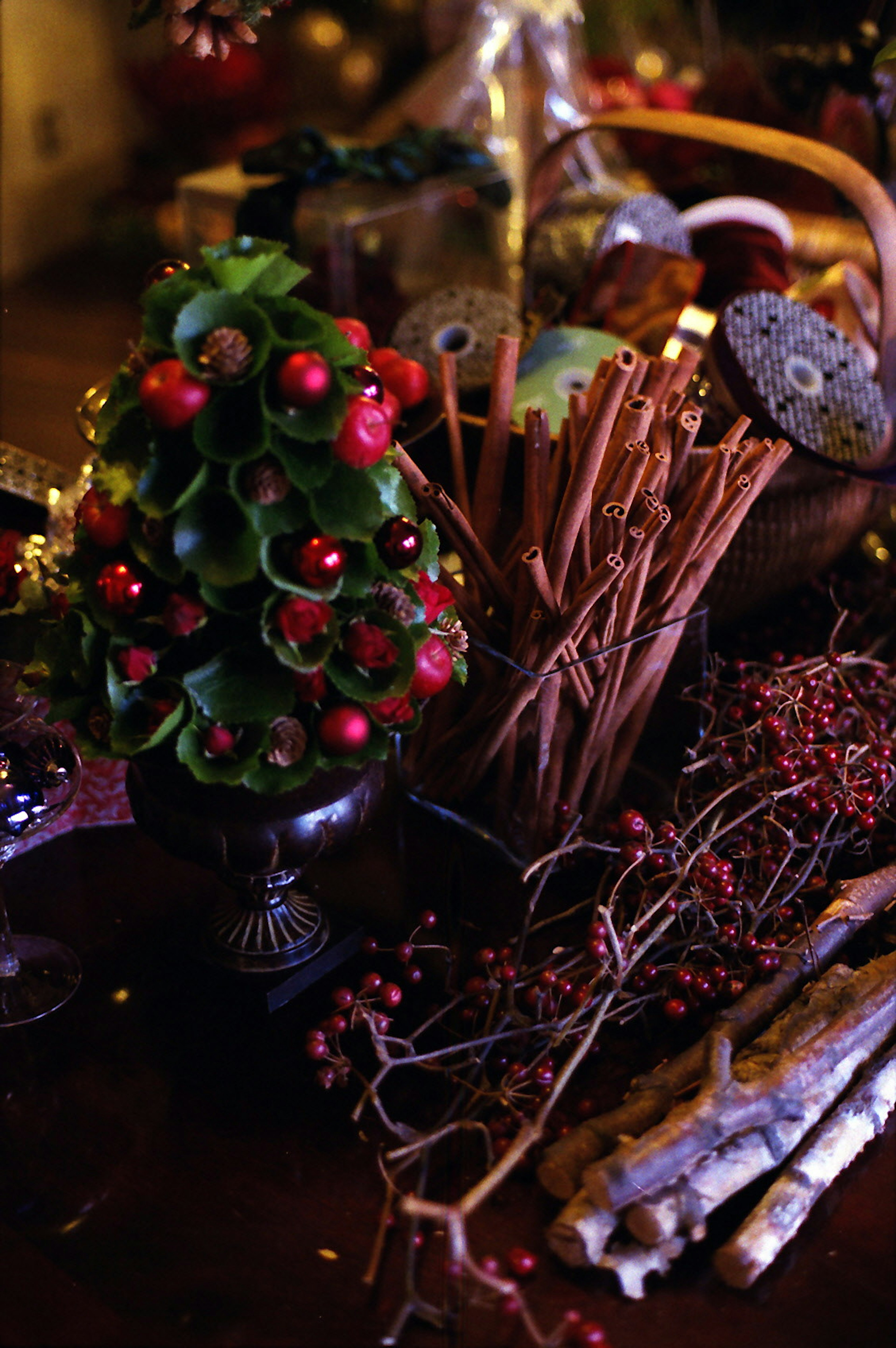 Pohon Natal kecil dekoratif dengan beri merah dan daun hijau di atas meja