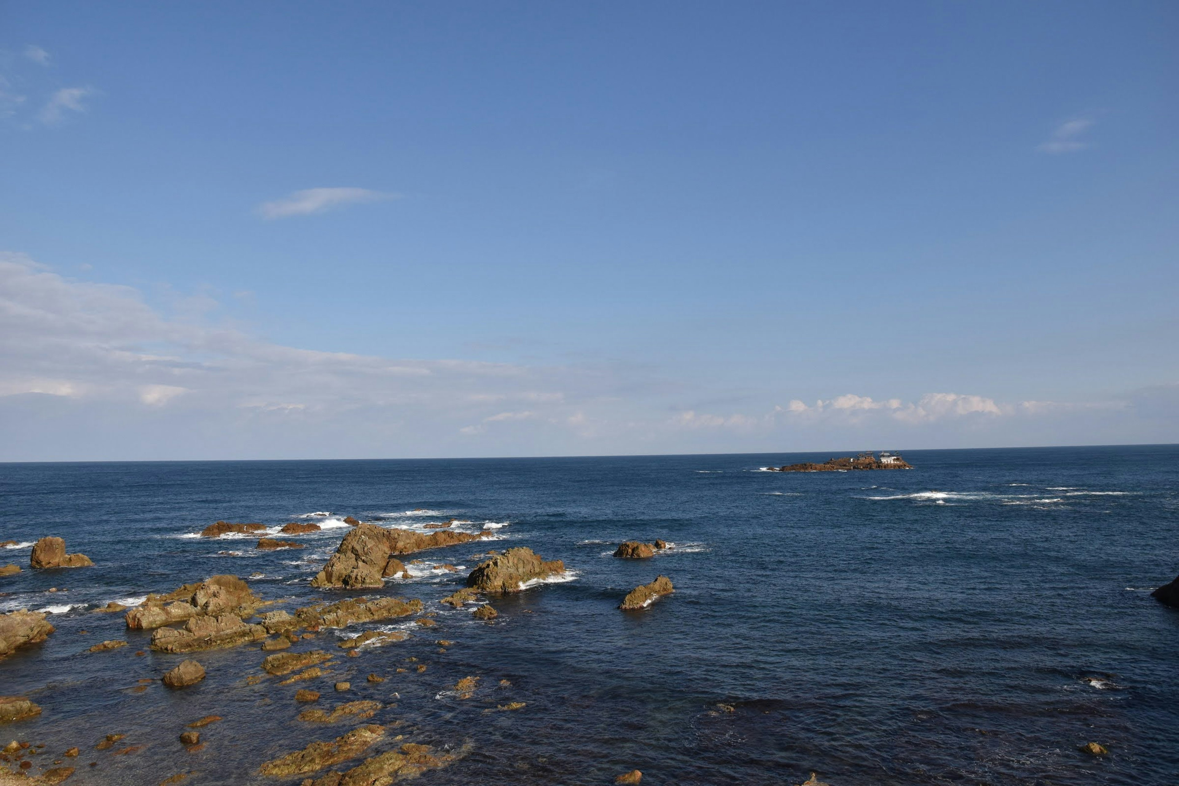 Pemandangan laut biru dan garis pantai berbatu