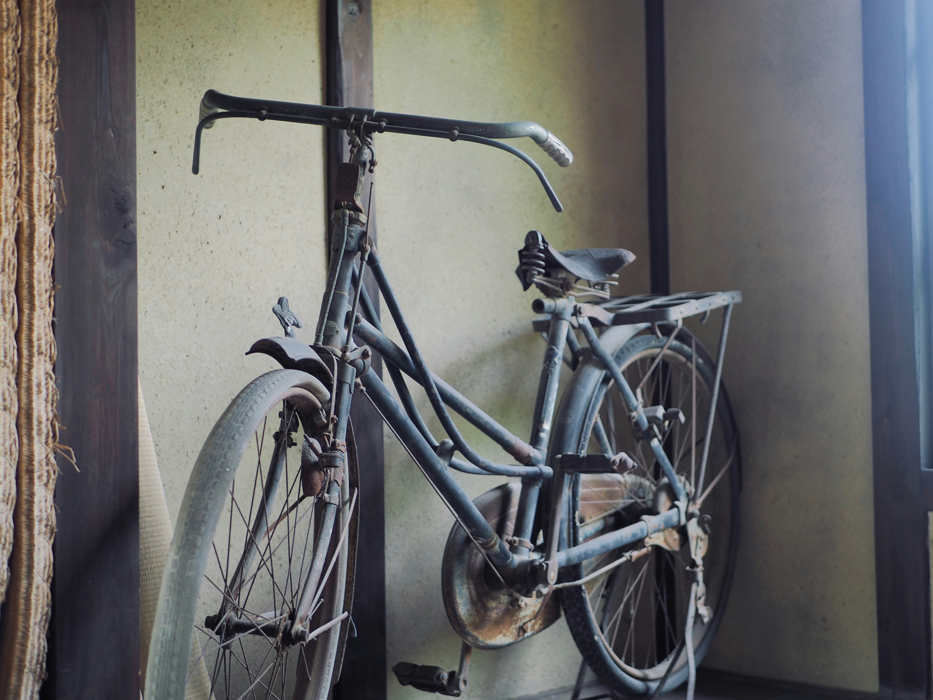 An old bicycle leaning against a wall in a simple indoor setting