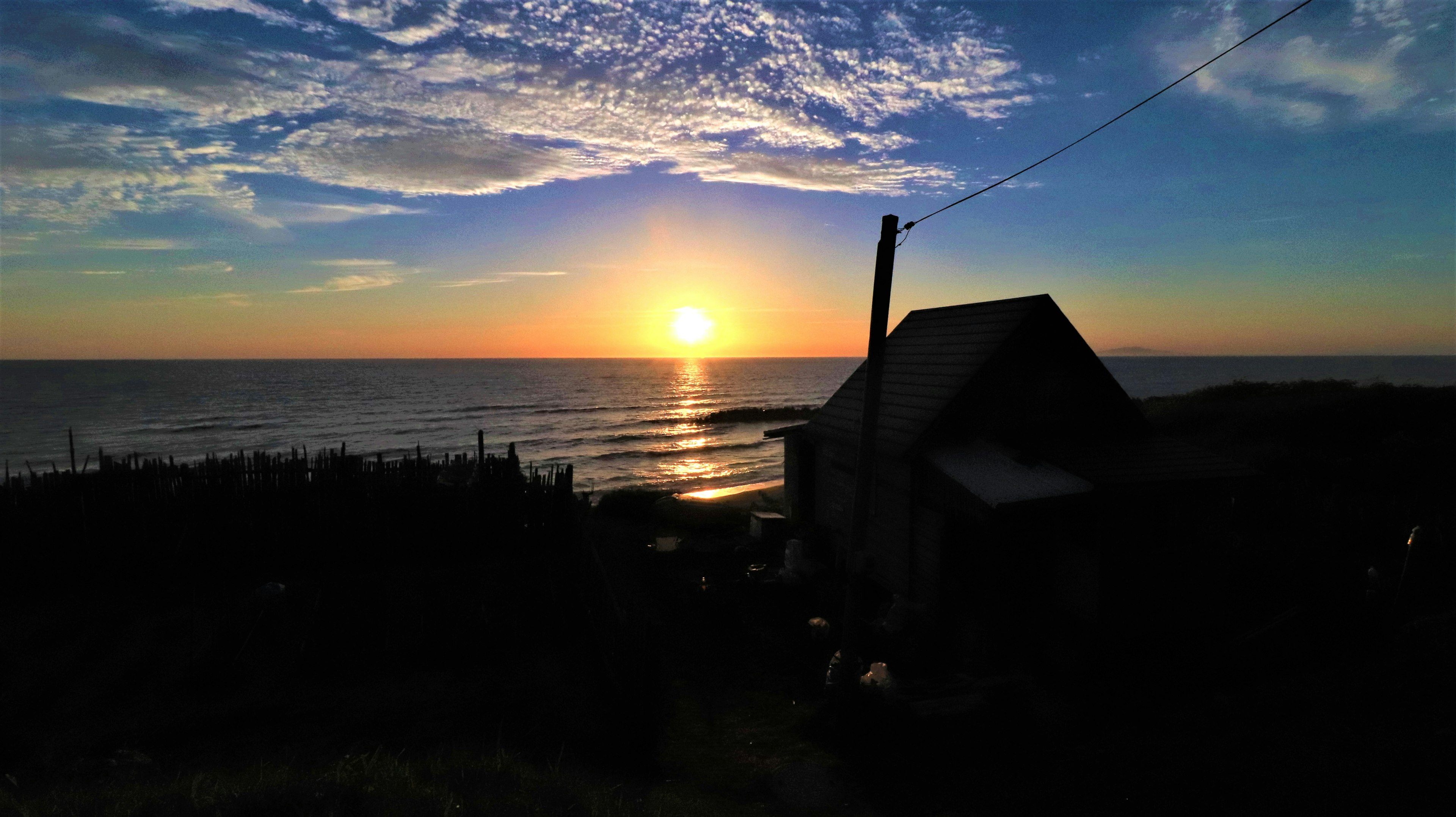 夕日が海に沈む風景と家のシルエット