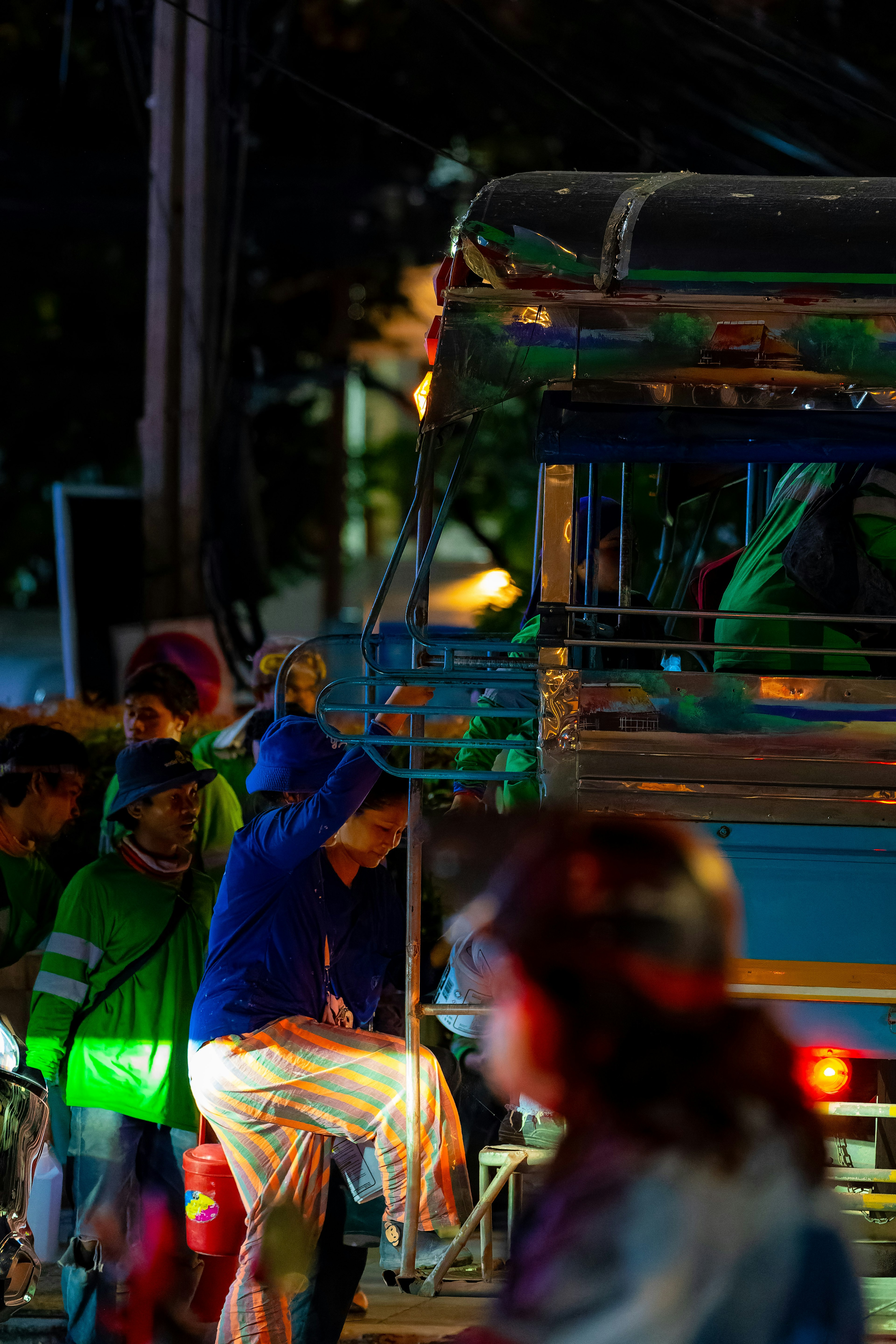 夜间城市场景中人们登上蓝色卡车