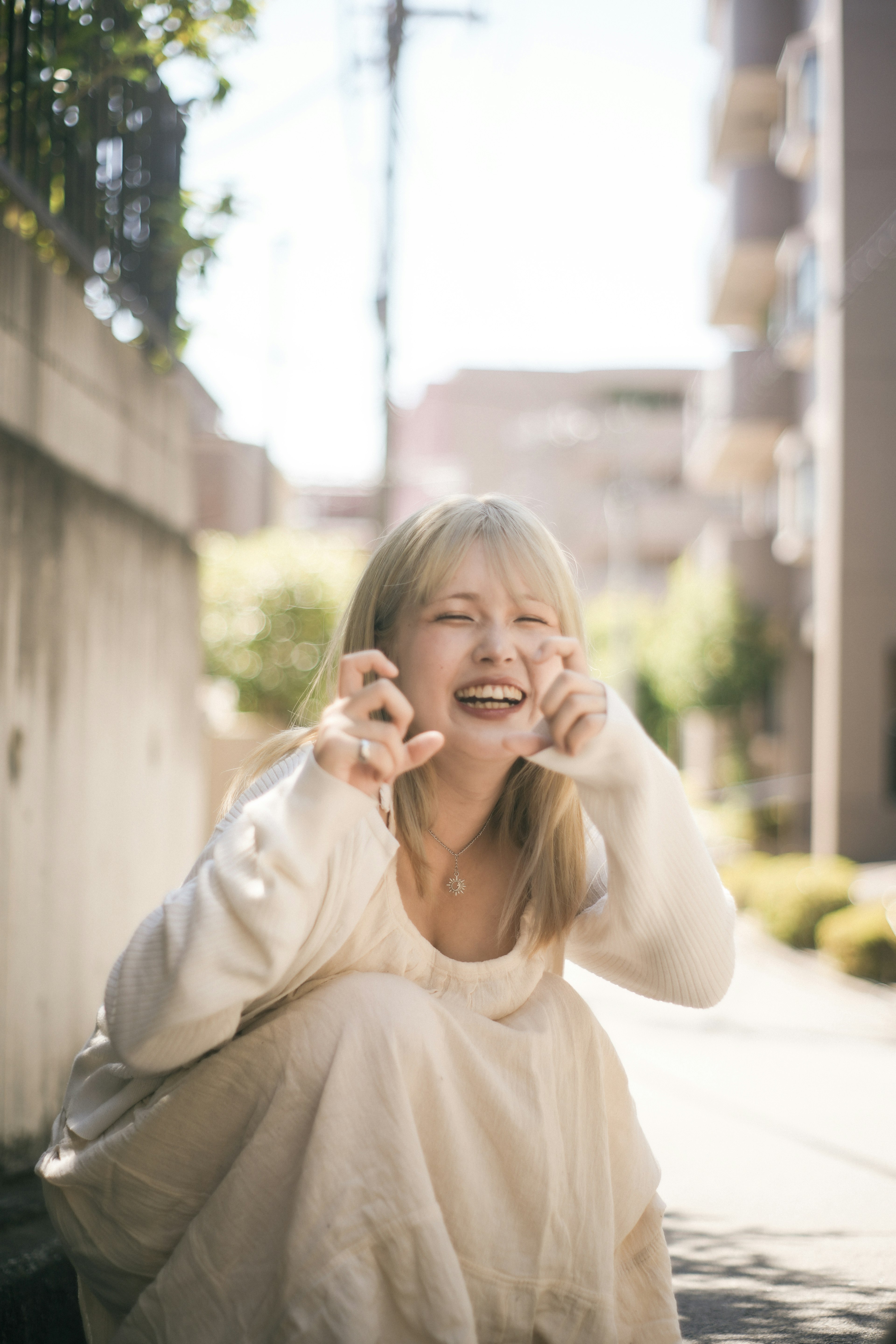 明るい日差しの中で白いドレスを着ている女性が笑顔でポーズをとっている