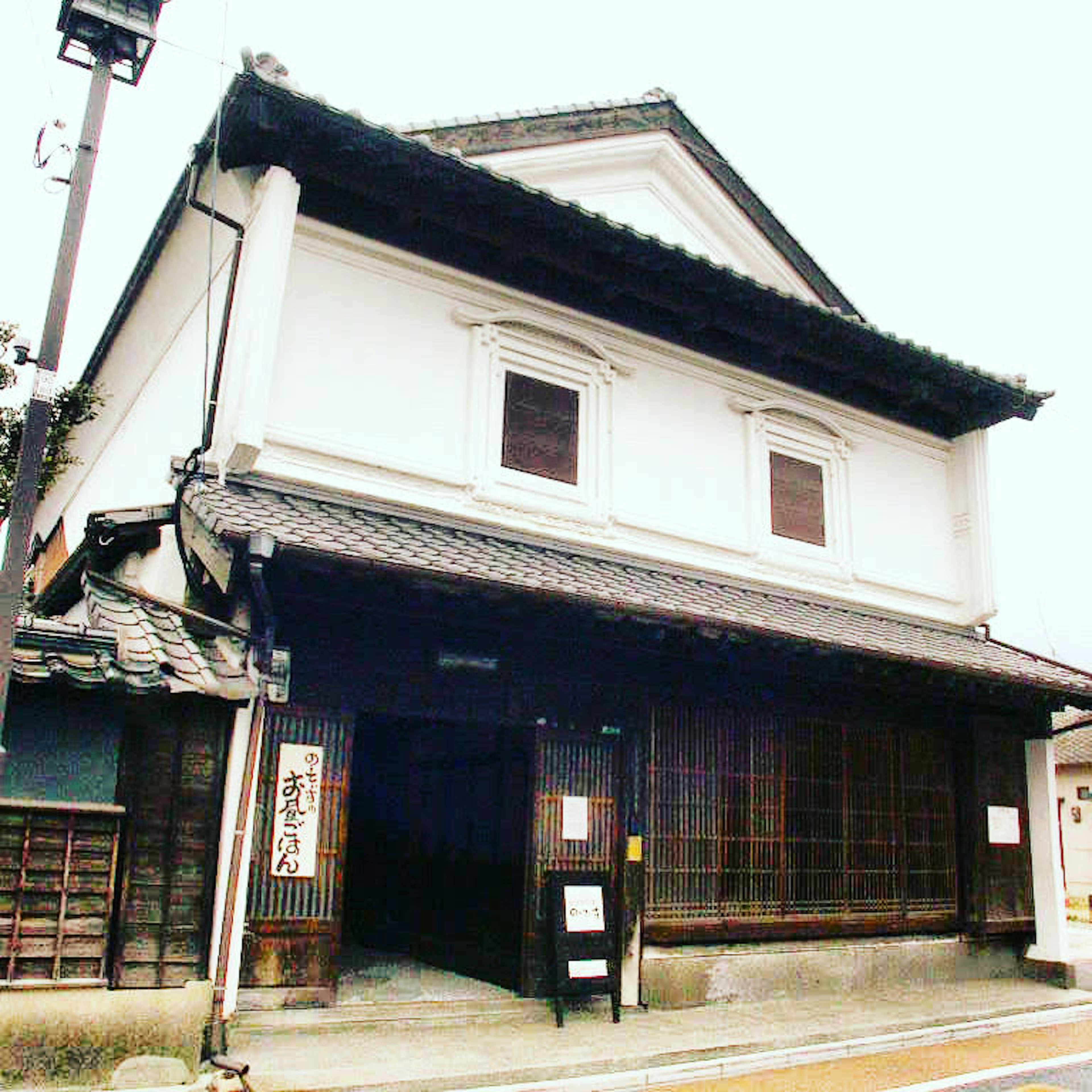 Exterior de un edificio japonés tradicional con paredes blancas y ventanas de madera, techo de tejas