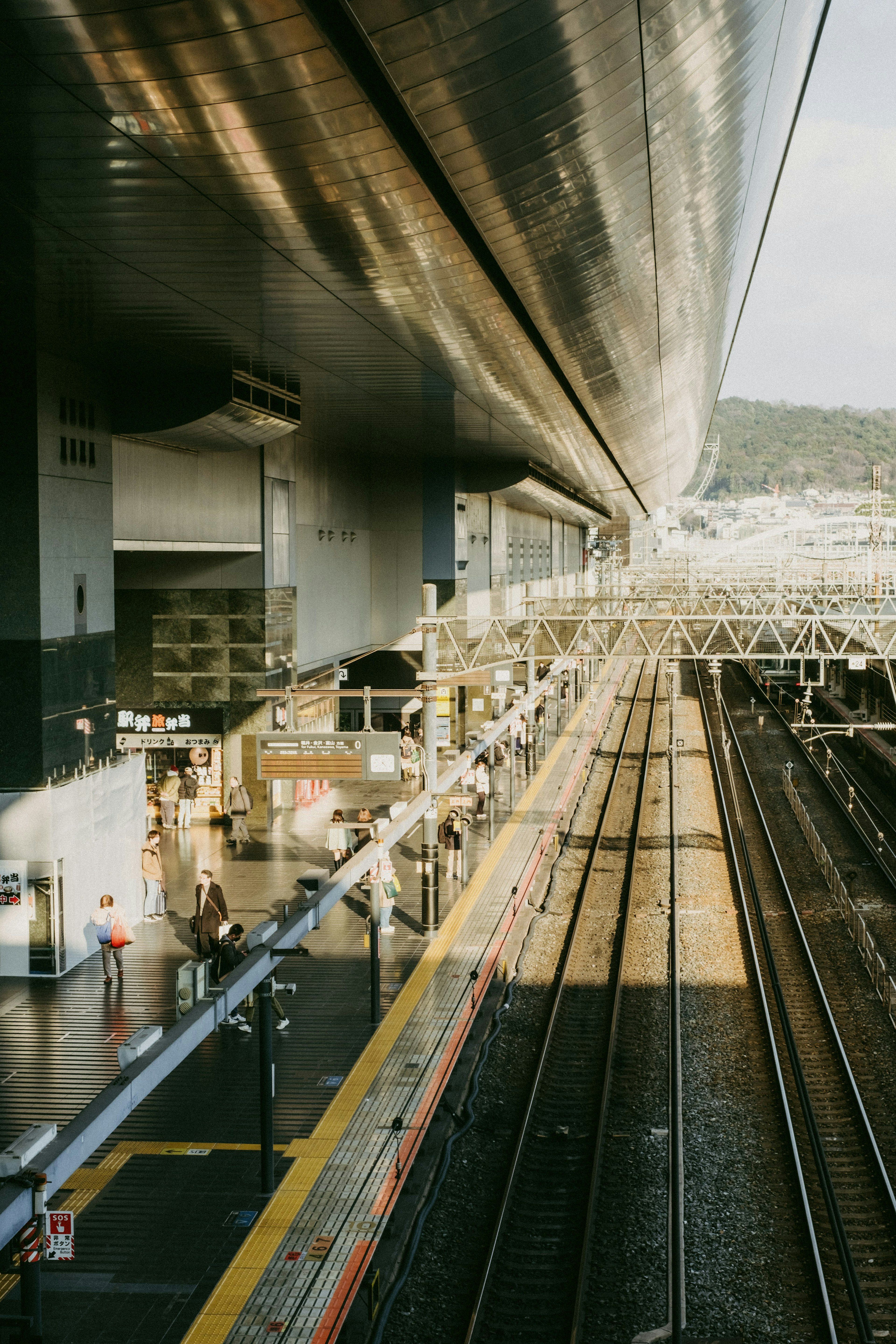 Pemandangan platform stasiun kereta dan rel dengan sinar matahari menerangi area