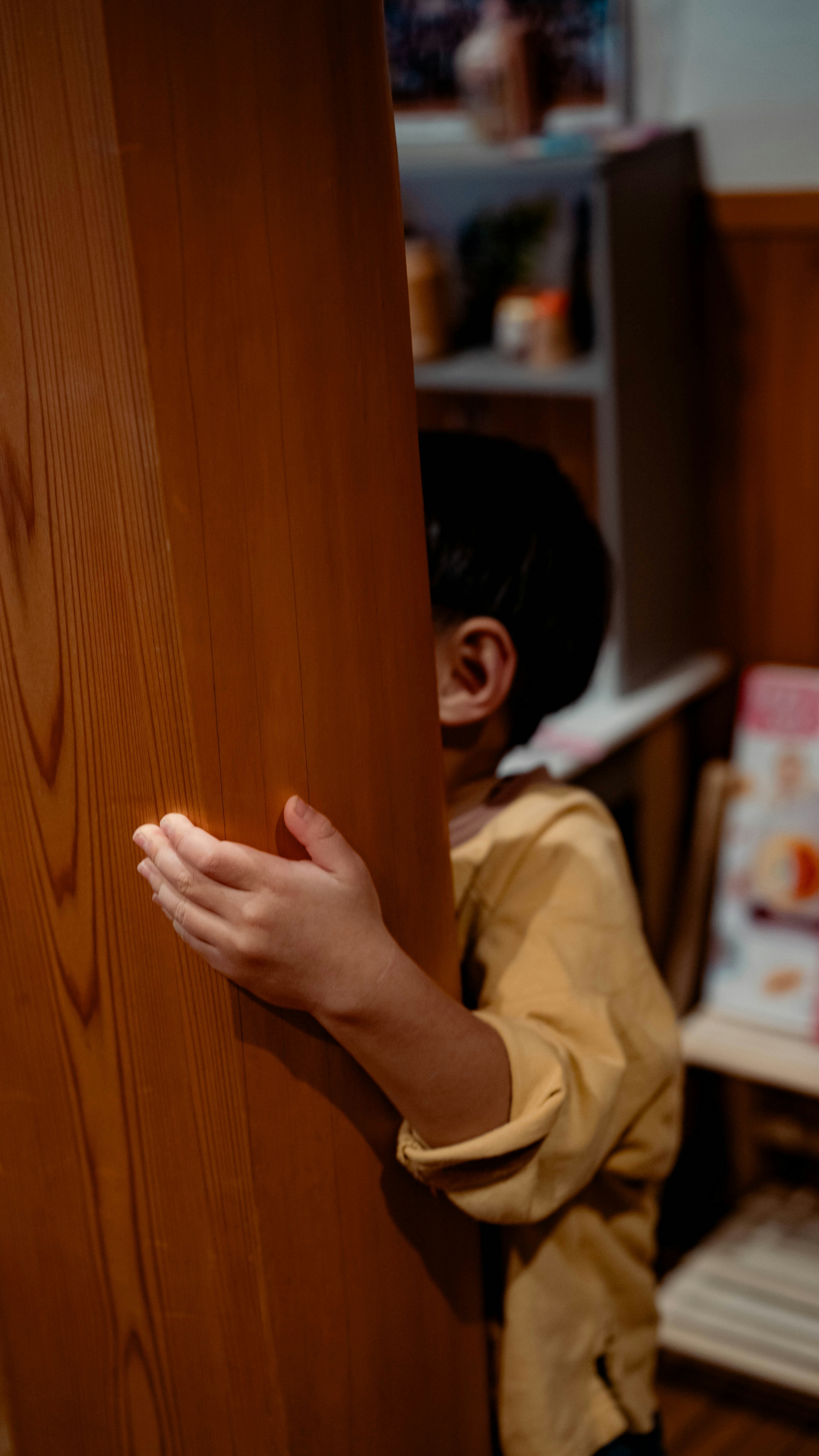 Enfant caché derrière un pilier en bois avec une expression ludique