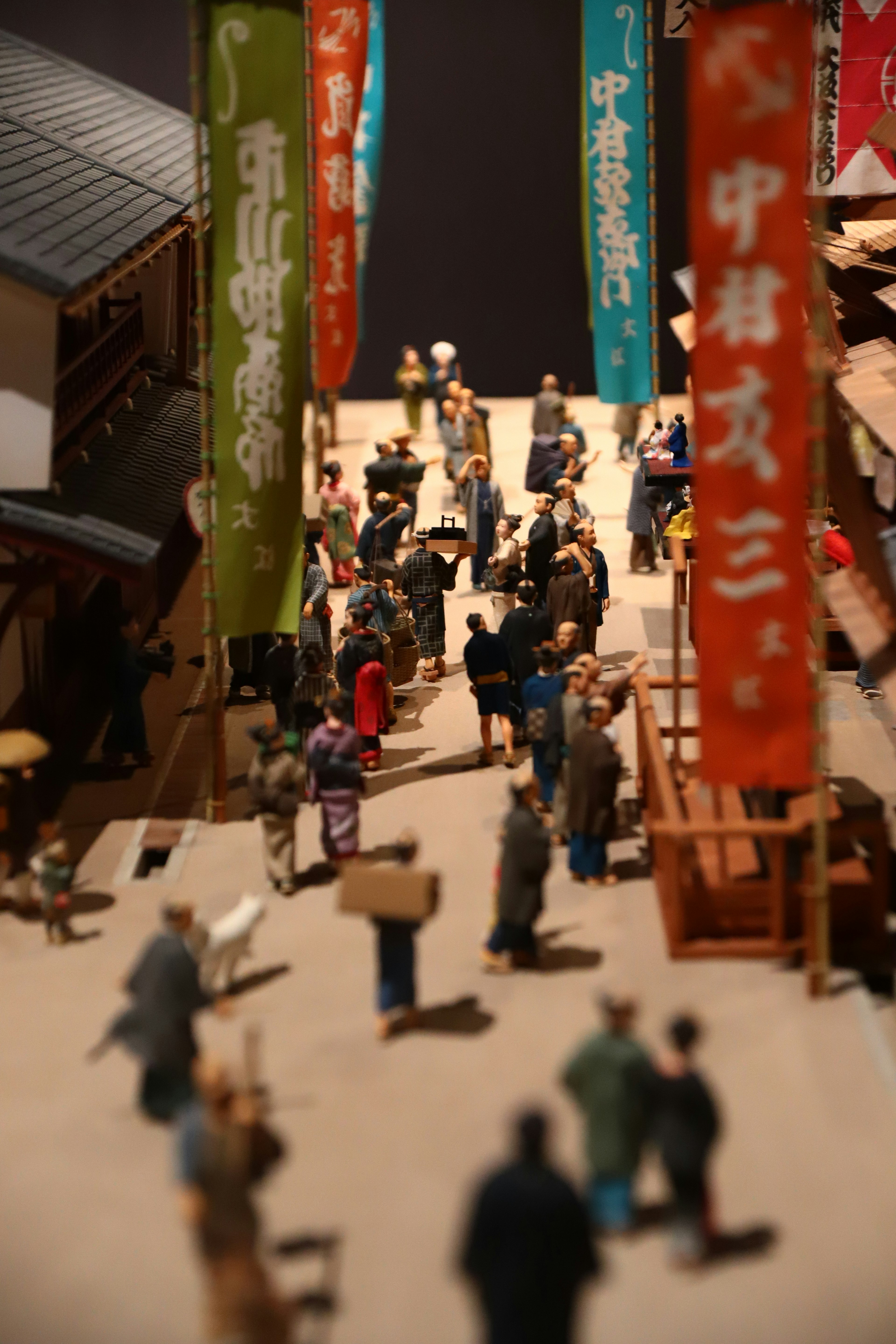 A miniature street scene with people walking and colorful banners