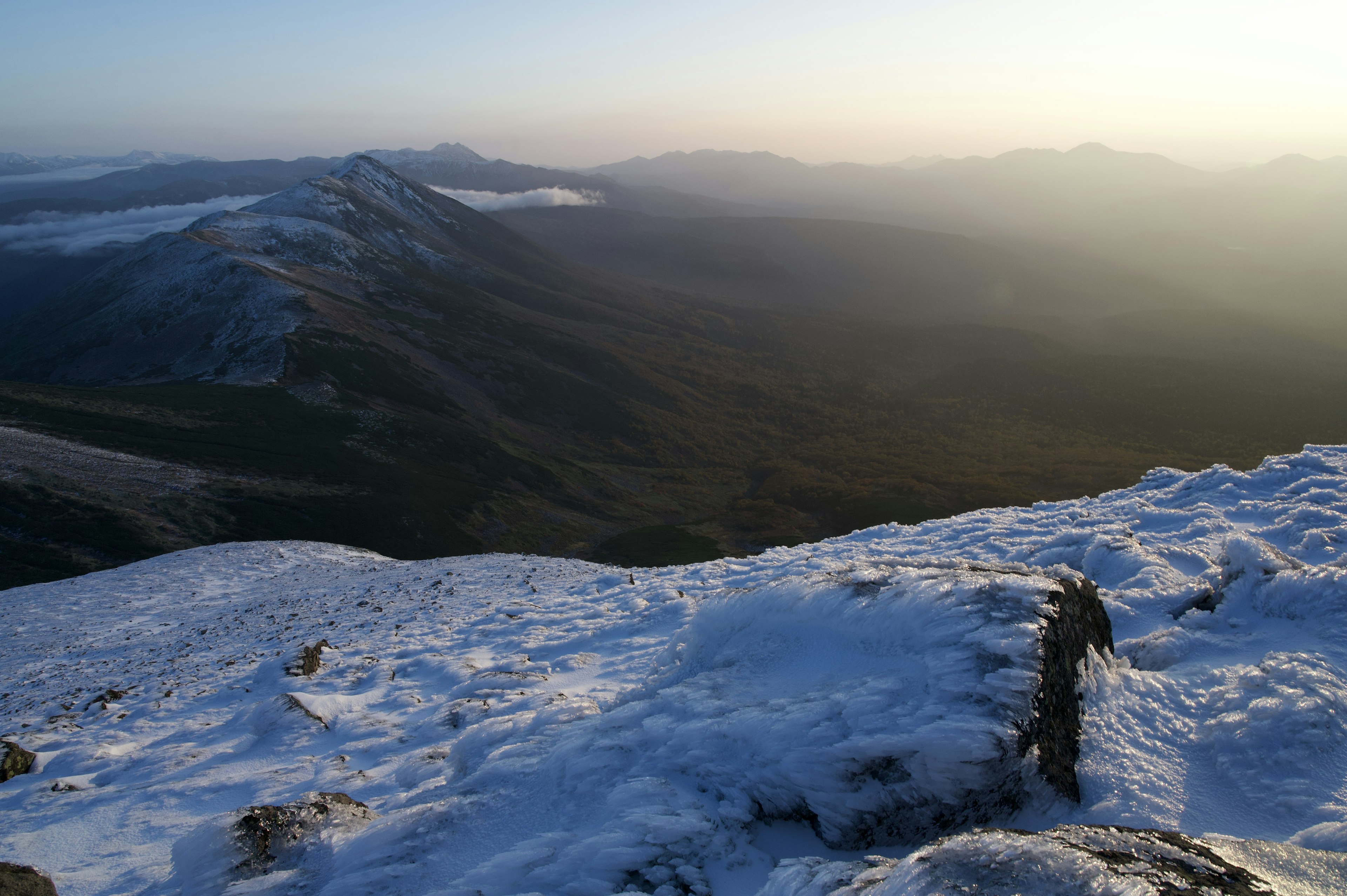 Snow-covered mountain peak view with misty mountains in the background