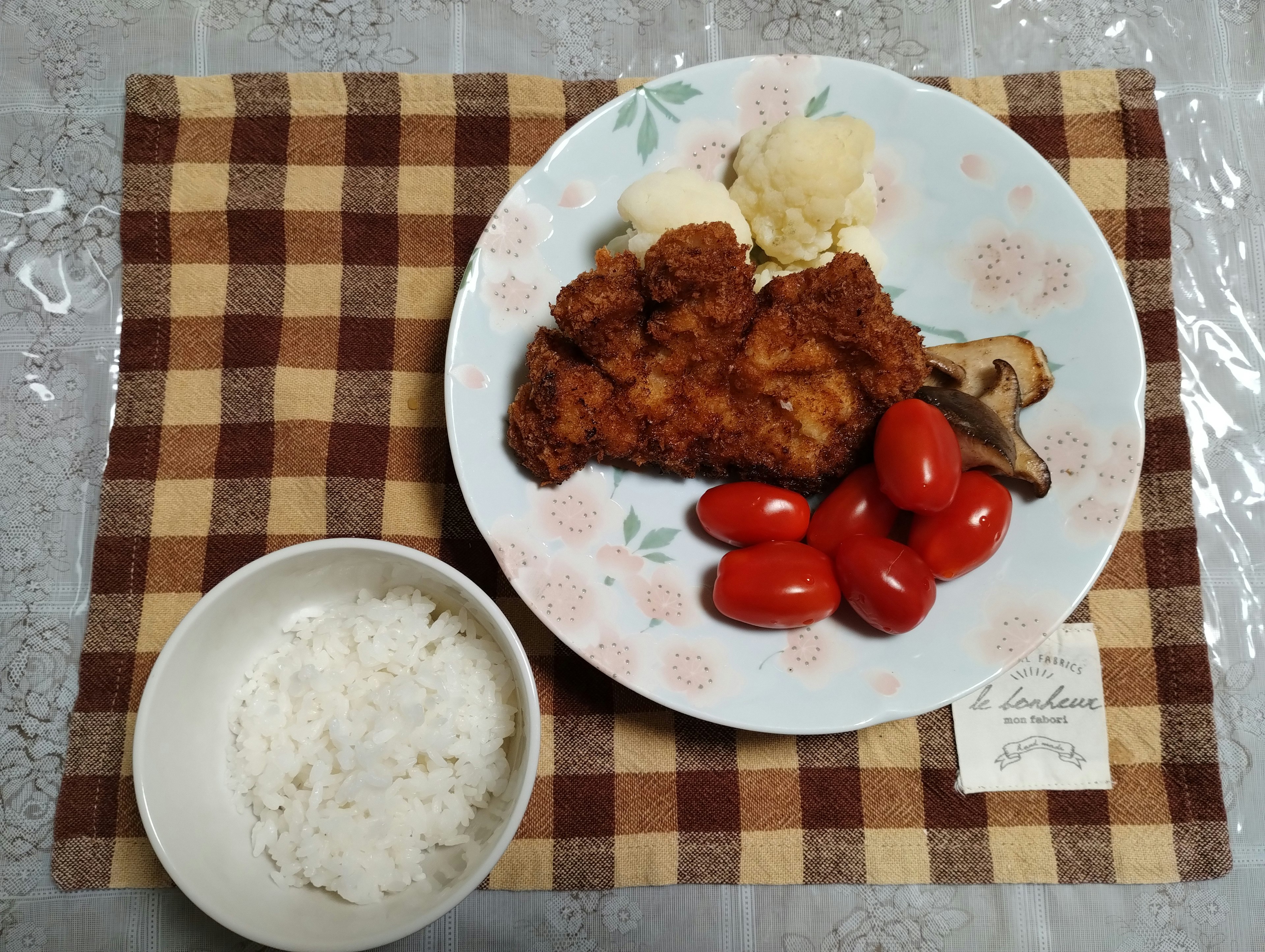 Frittierte Hähnchenstücke mit Cherrytomaten und Kartoffelpüree auf einem blumigen Teller serviert