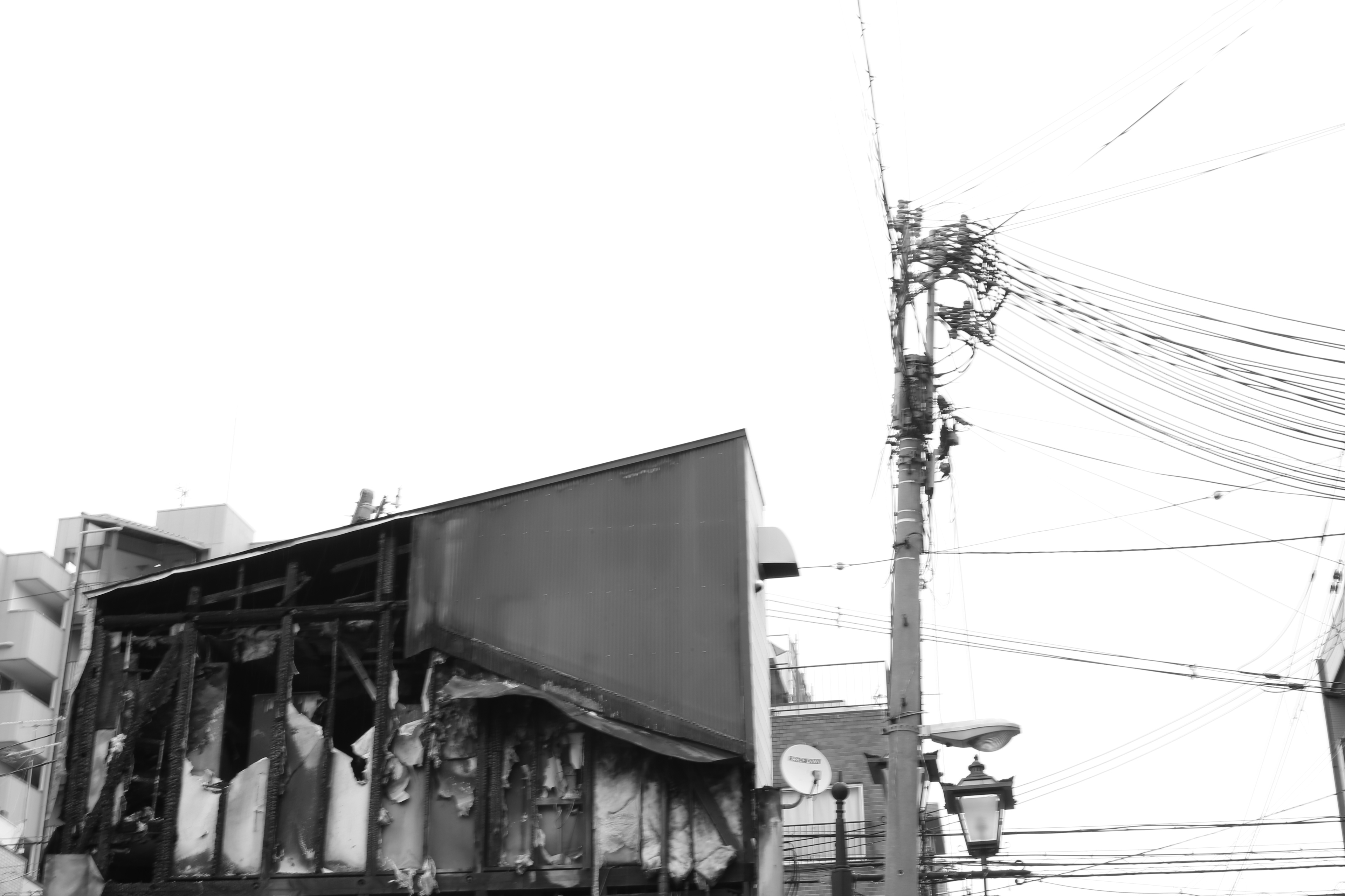 Black and white image of a burnt billboard and utility pole