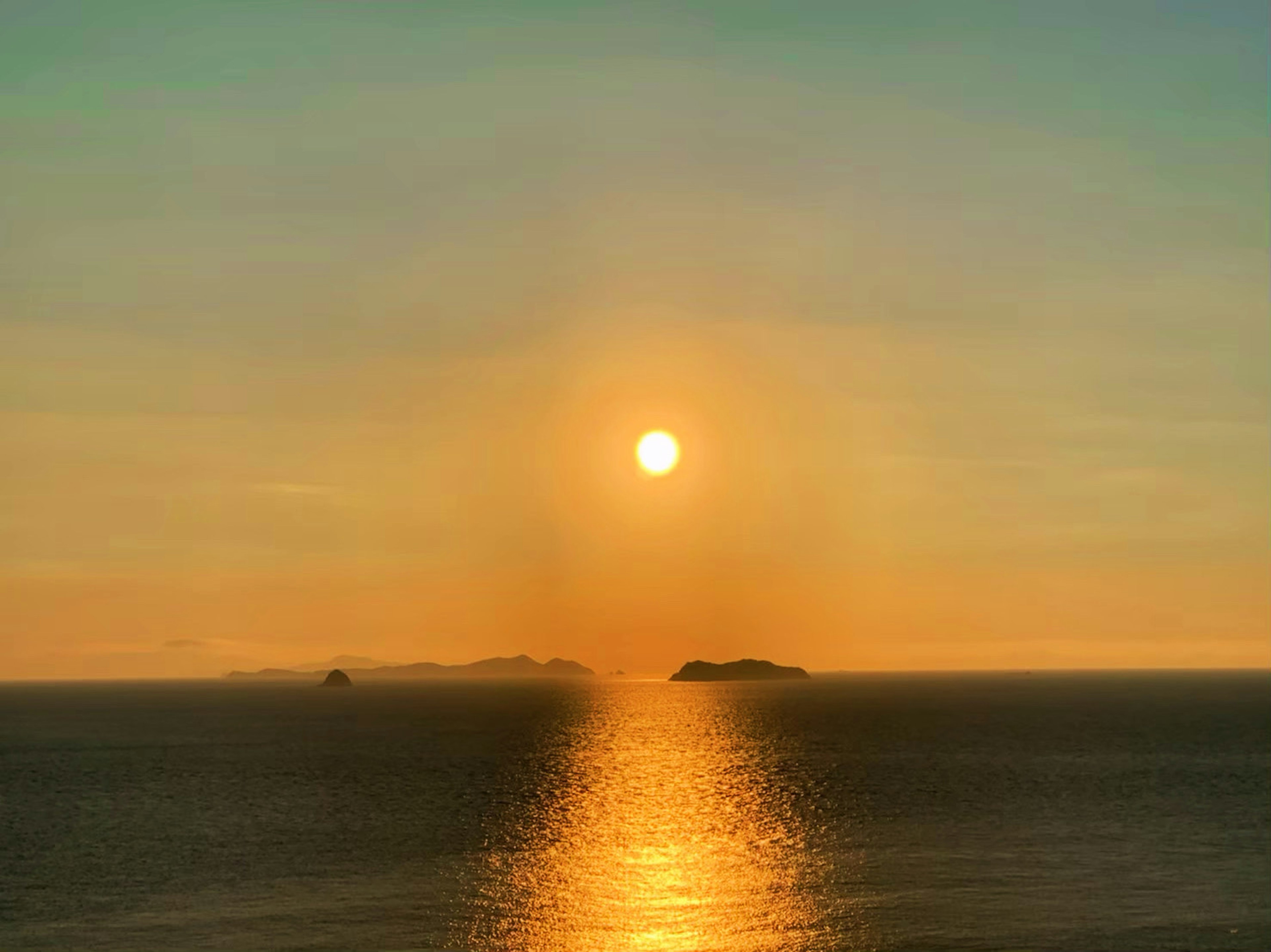 夕日が海に沈む風景と静かな島々