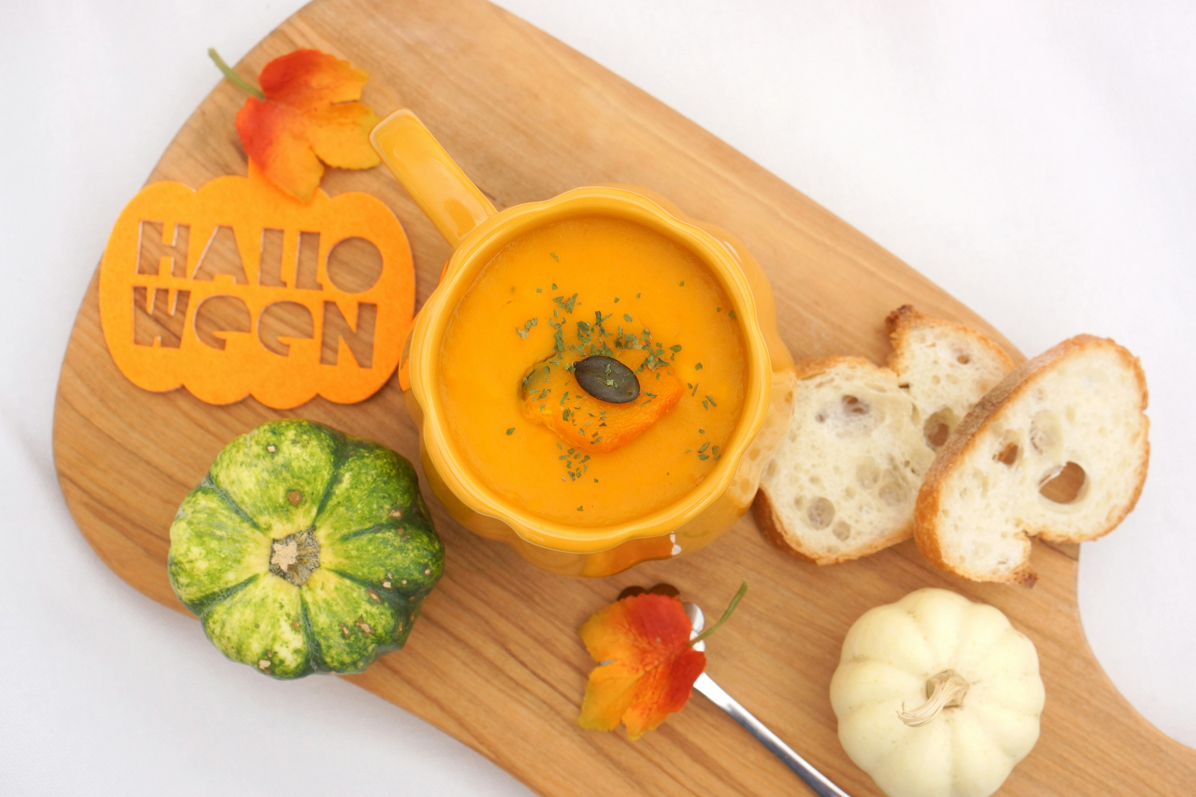 Halloween themed pumpkin soup served with bread and decorative gourds